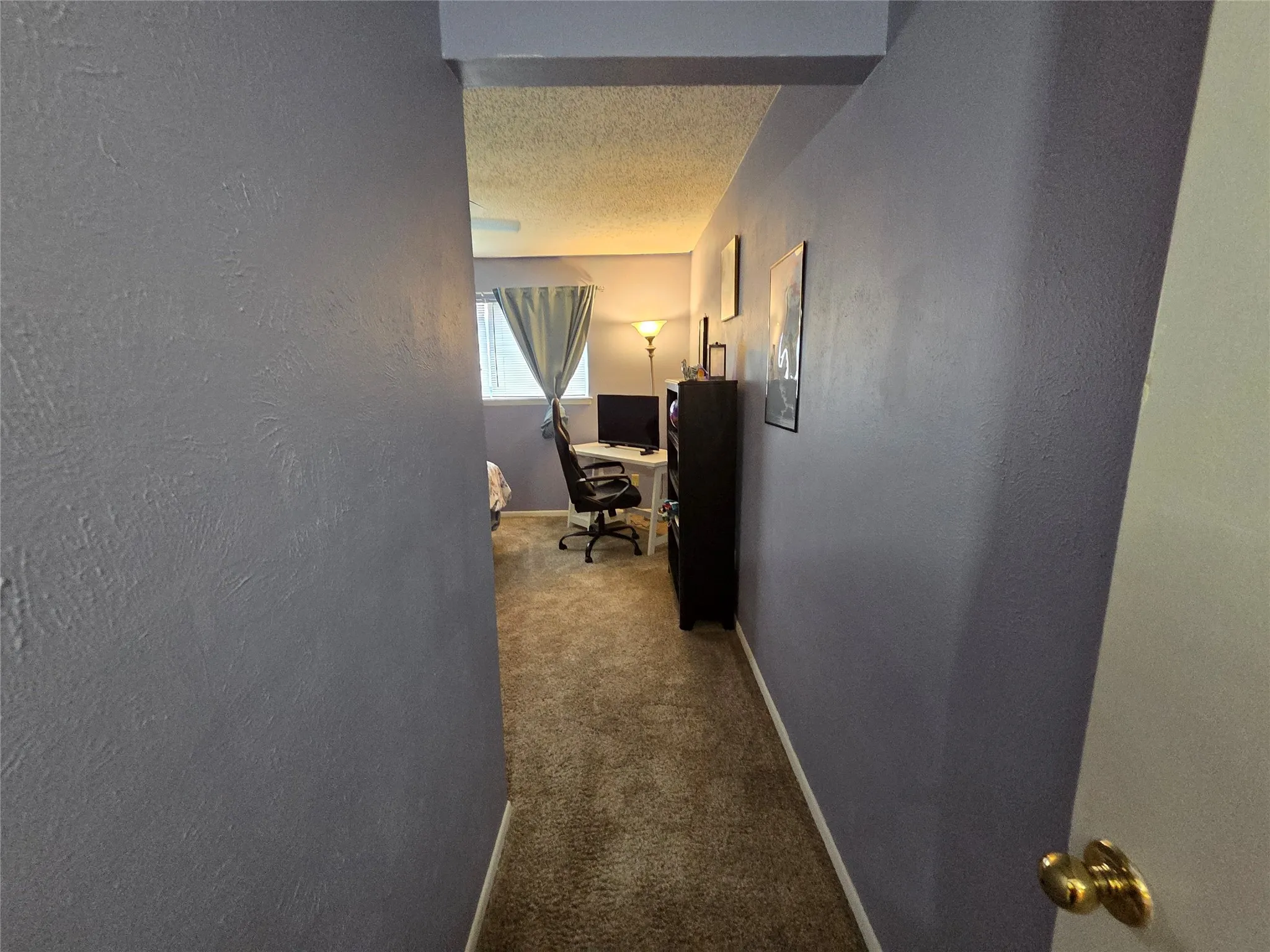 Hallway featuring textured walls and carpet flooring