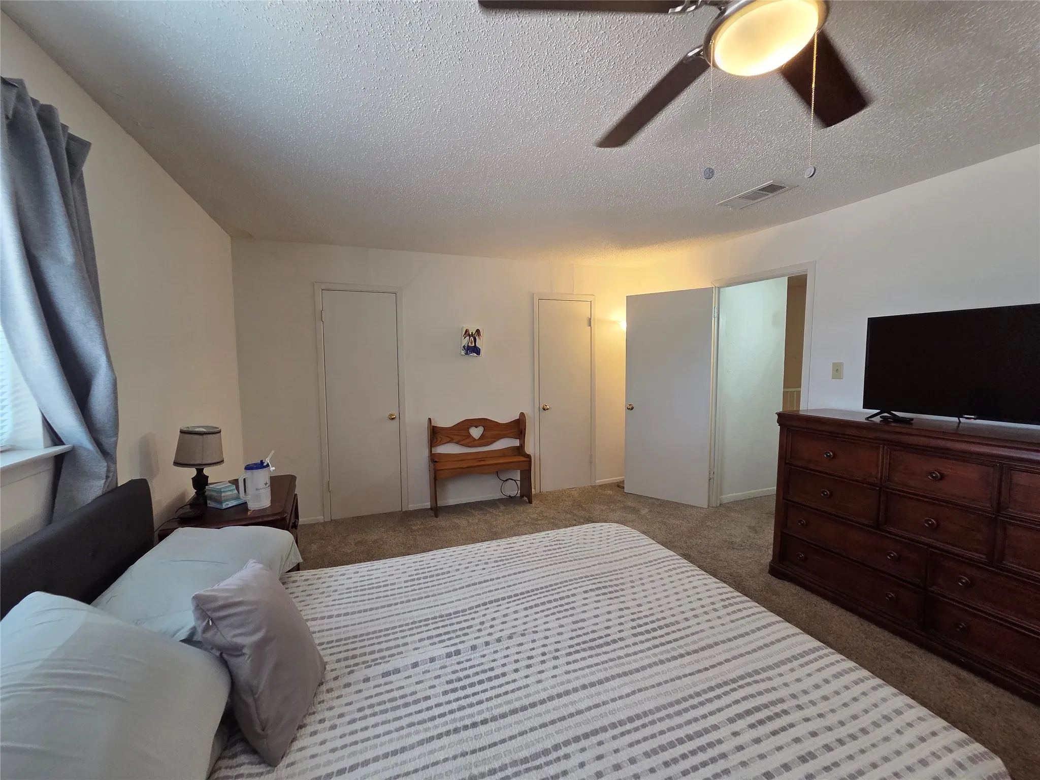 Spacious room featuring neutral carpeting, a ceiling fan with integrated lighting, and multiple doors providing access to additional spaces