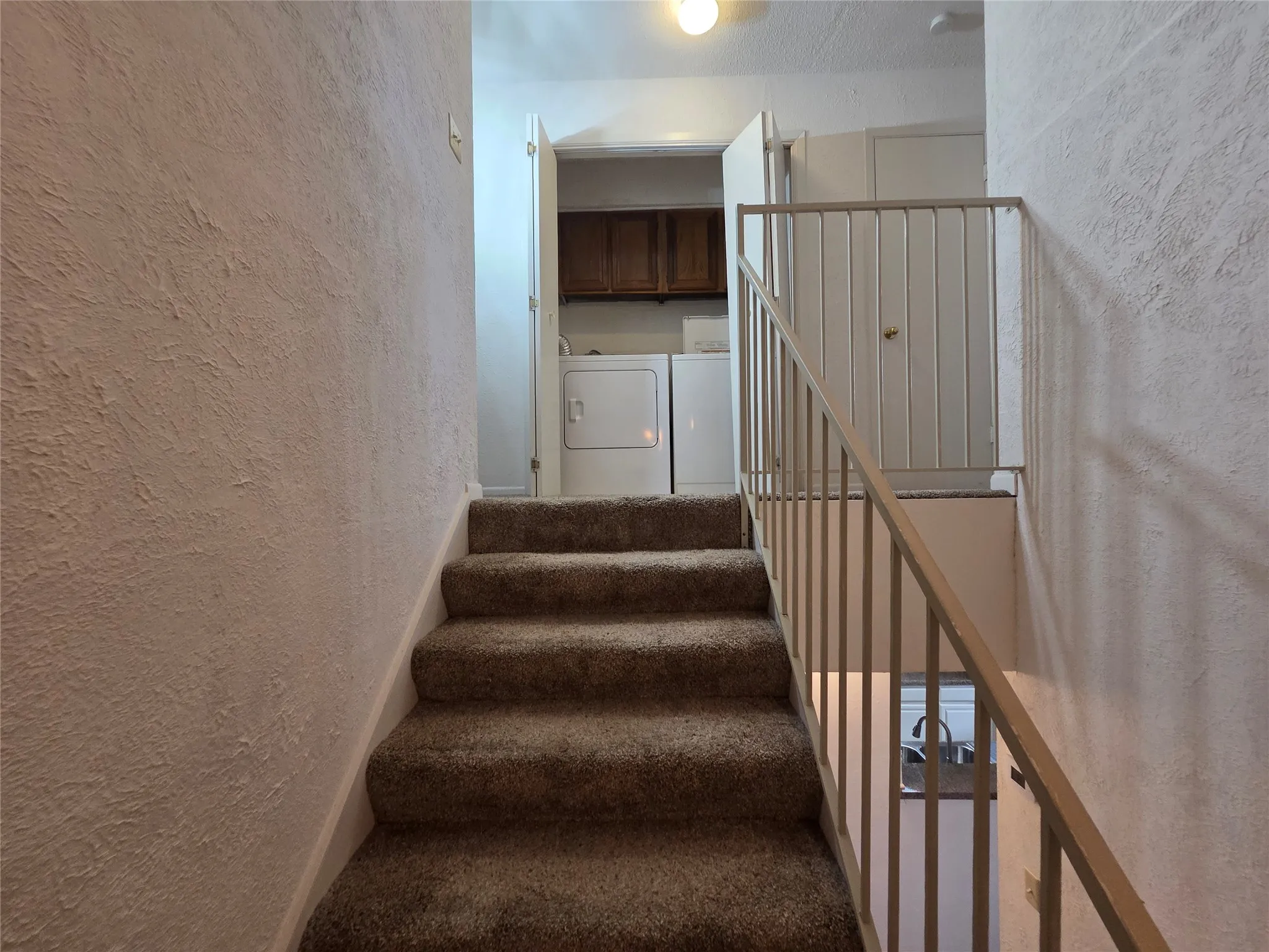 Staircase featuring carpeted treads and a metal railing