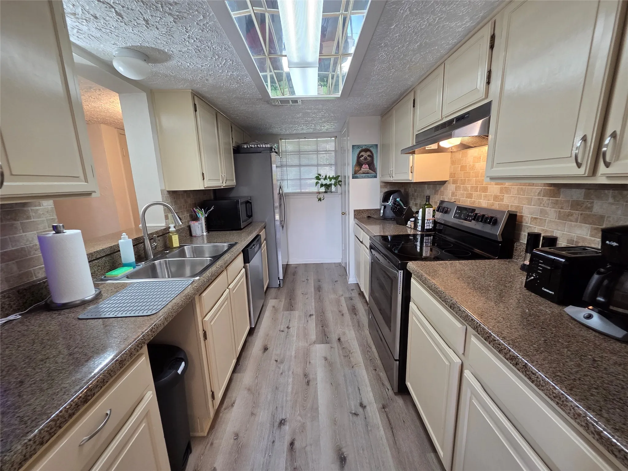 Galley kitchen featuring light wood-finish flooring, cream cabinetry, and contrasting countertops