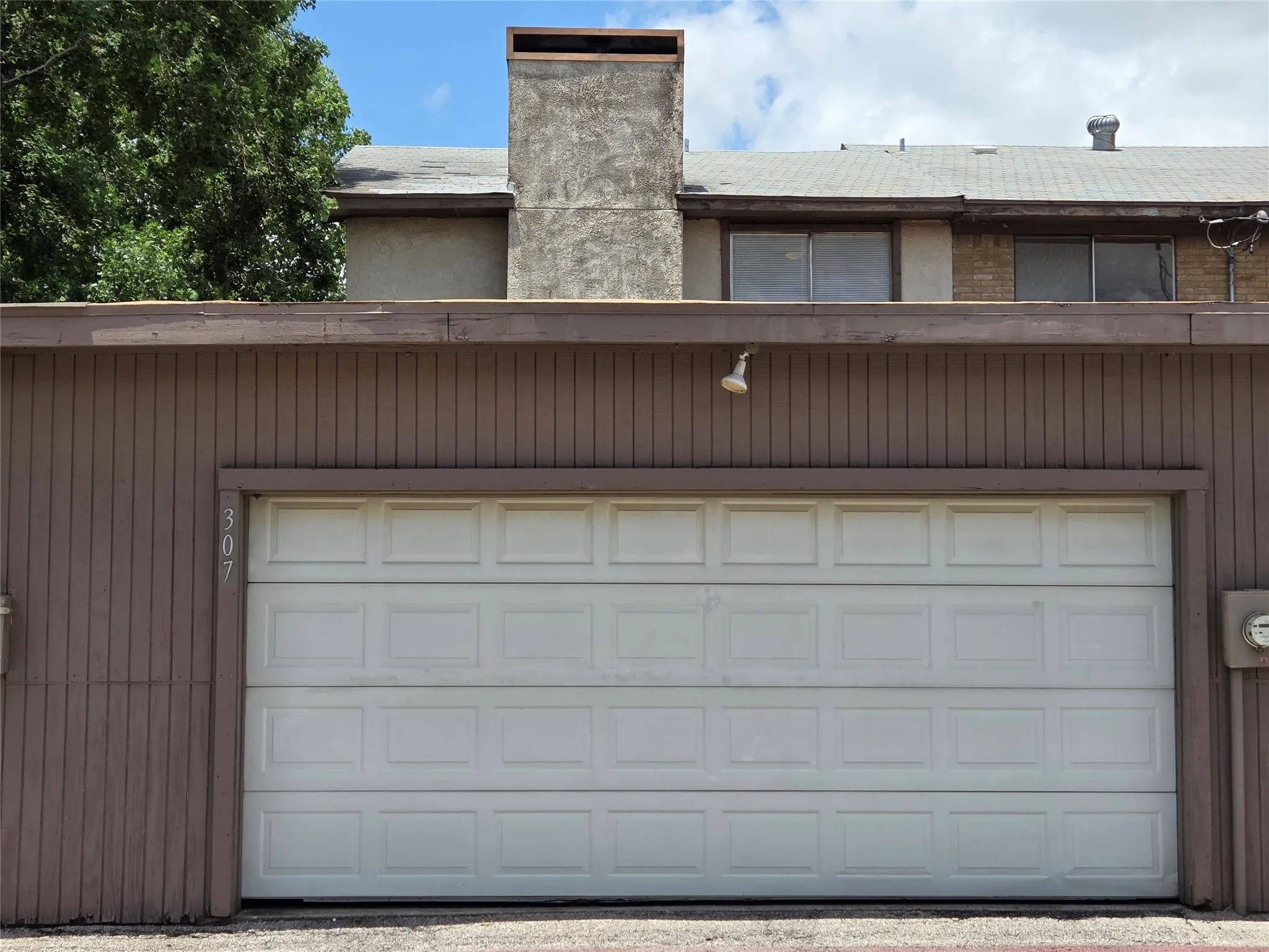 Property exterior featuring a paneled garage door, vertical wood siding, and an upper-level window