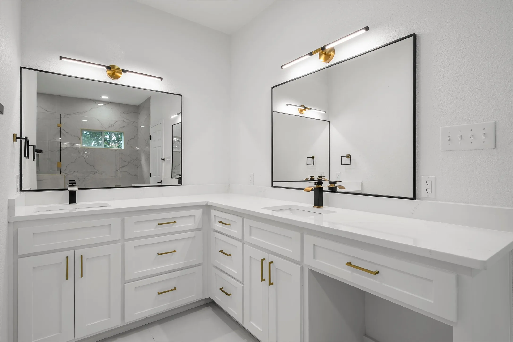 Dual vanity featuring white cabinetry with gold-tone hardware, white countertops, rectangular undermount sinks, and matte black faucets