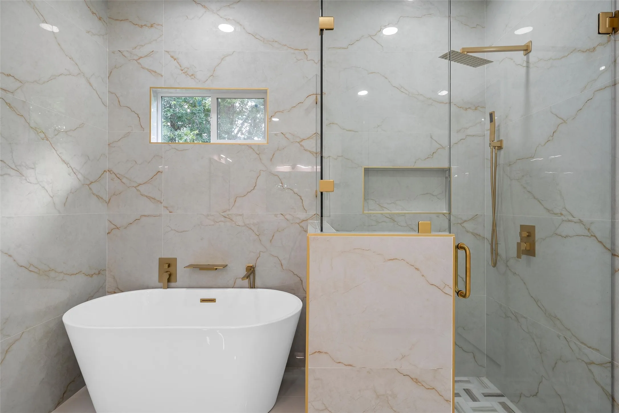 Freestanding soaking tub with gold-finish fixtures and an adjacent glass-enclosed shower