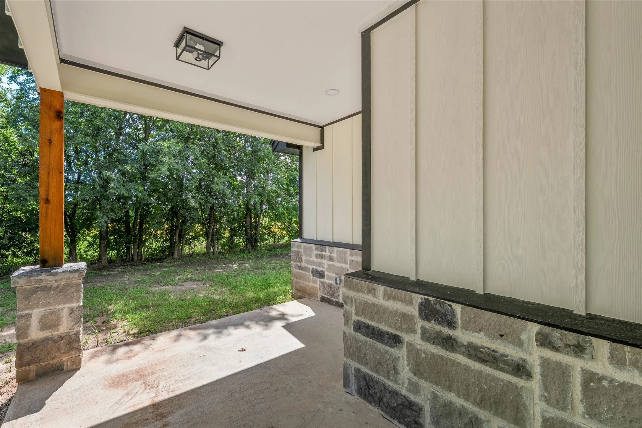 Covered porch with concrete flooring and a wood support beam