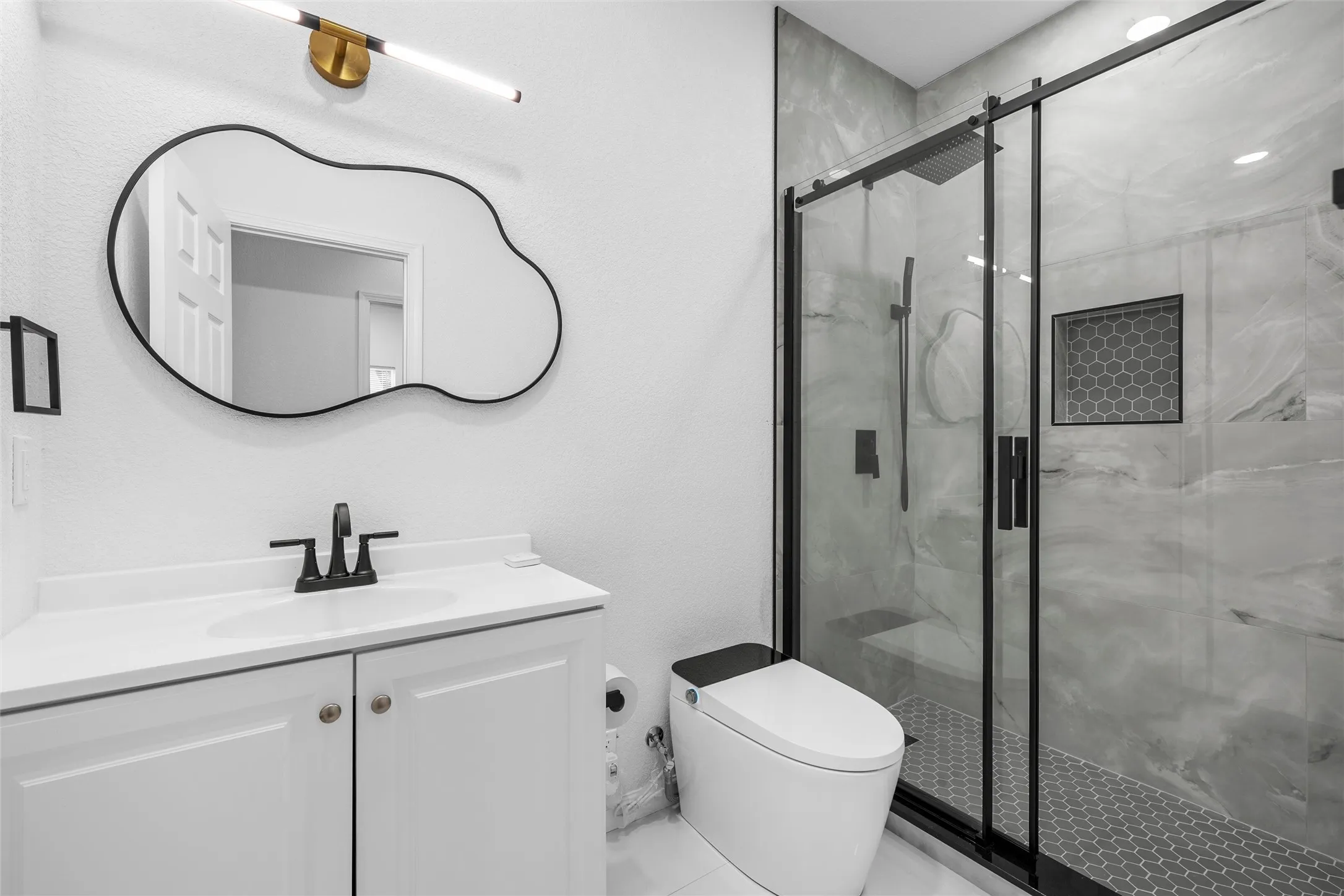 Contemporary bathroom featuring a white vanity with integrated sink, black faucet, and a decorative wall mirror