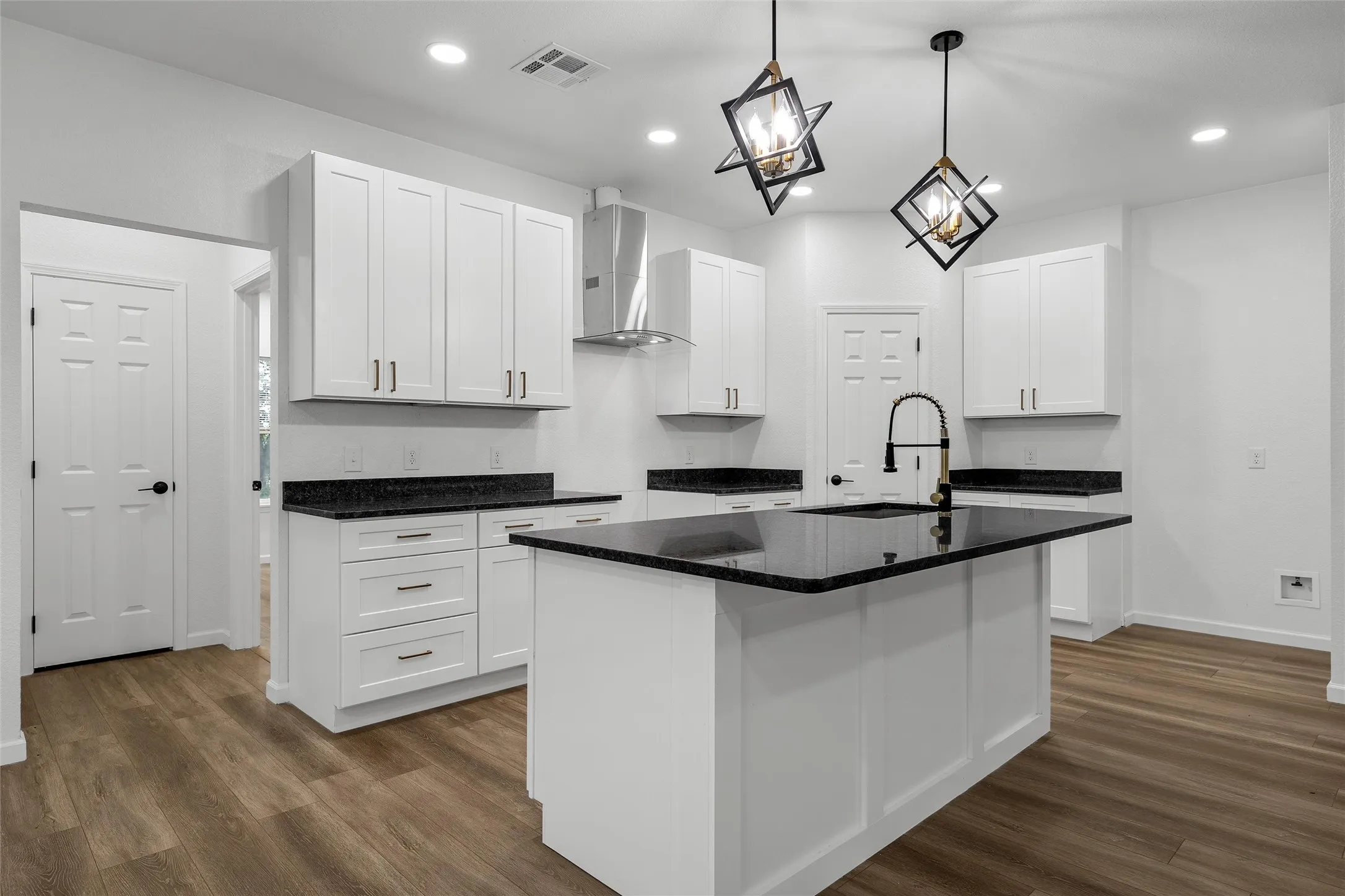 Modern kitchen featuring white cabinetry, dark countertops, and wood-finish flooring
