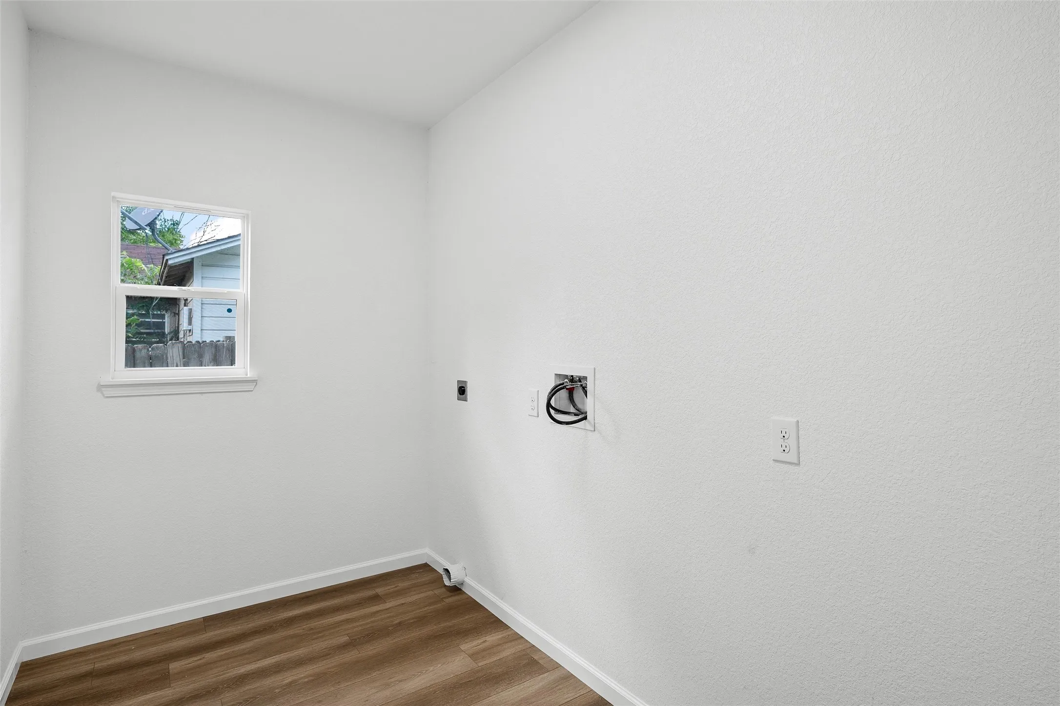 Dedicated utility space featuring wood-finish flooring, a single window, and a white baseboard trim