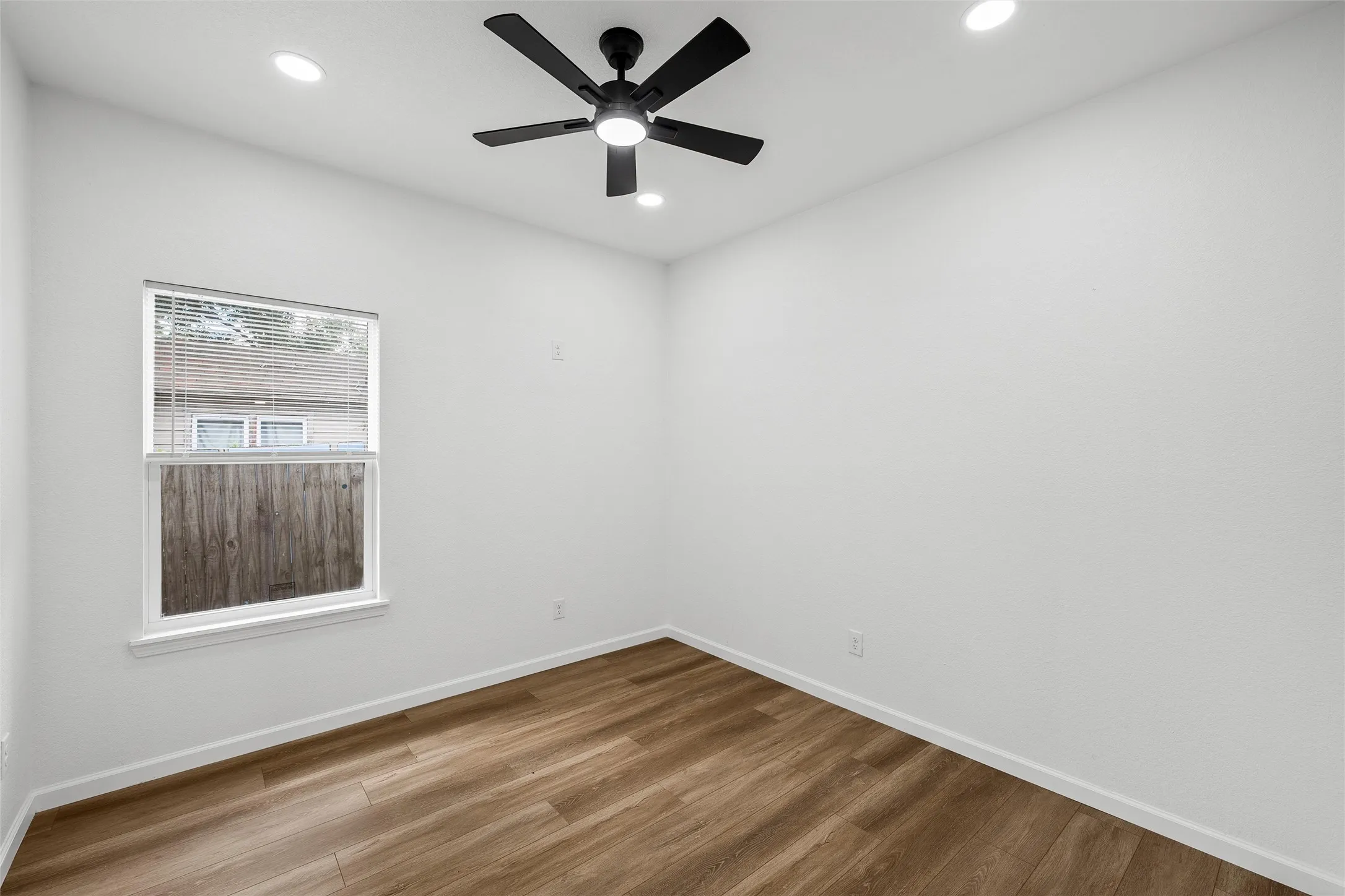 Bright room featuring wood-finish flooring, a contemporary ceiling fan, recessed lighting, and a single window with horizontal blinds