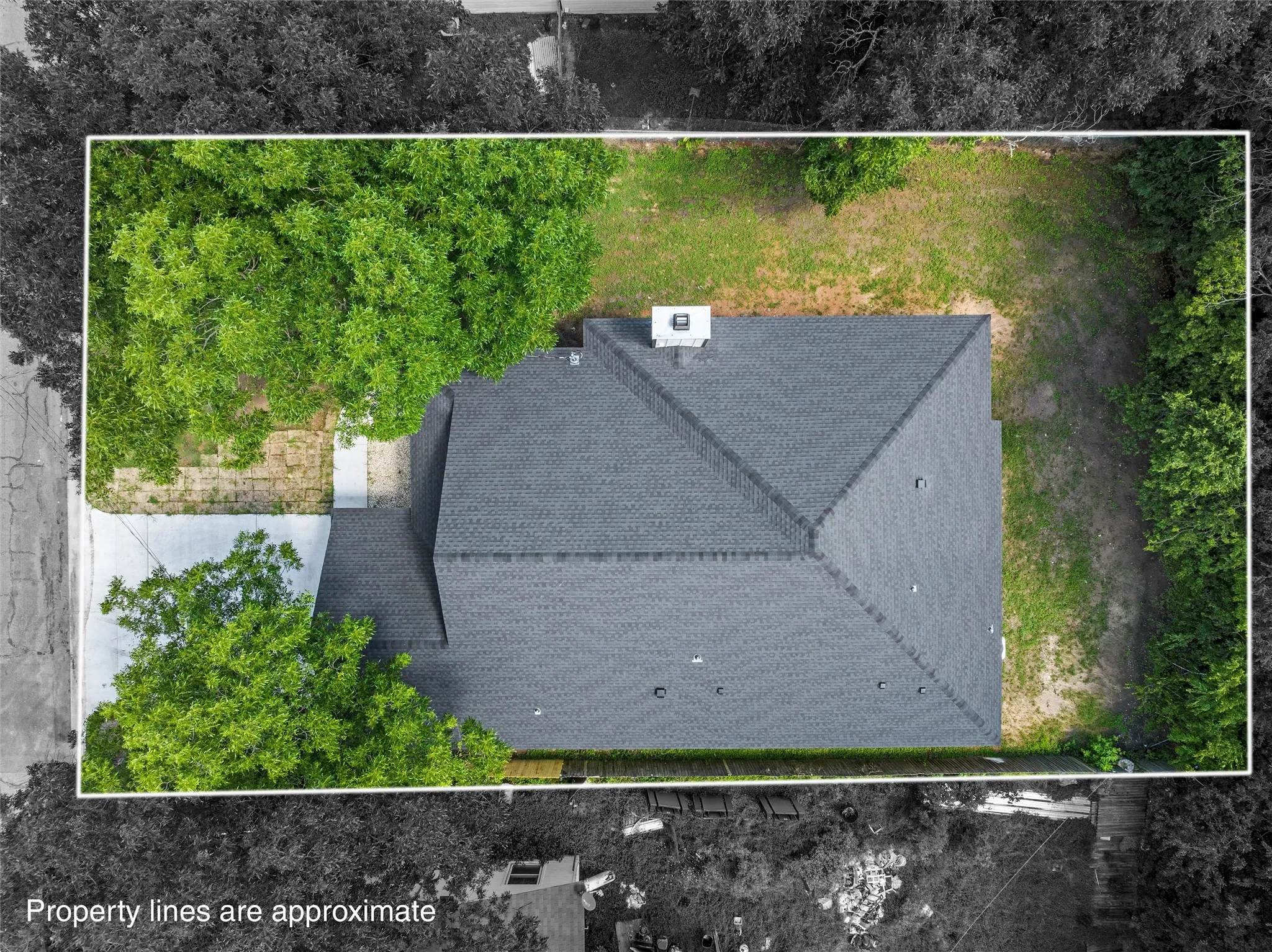 Overhead property view featuring a dark shingle roof, chimney, and surrounding trees