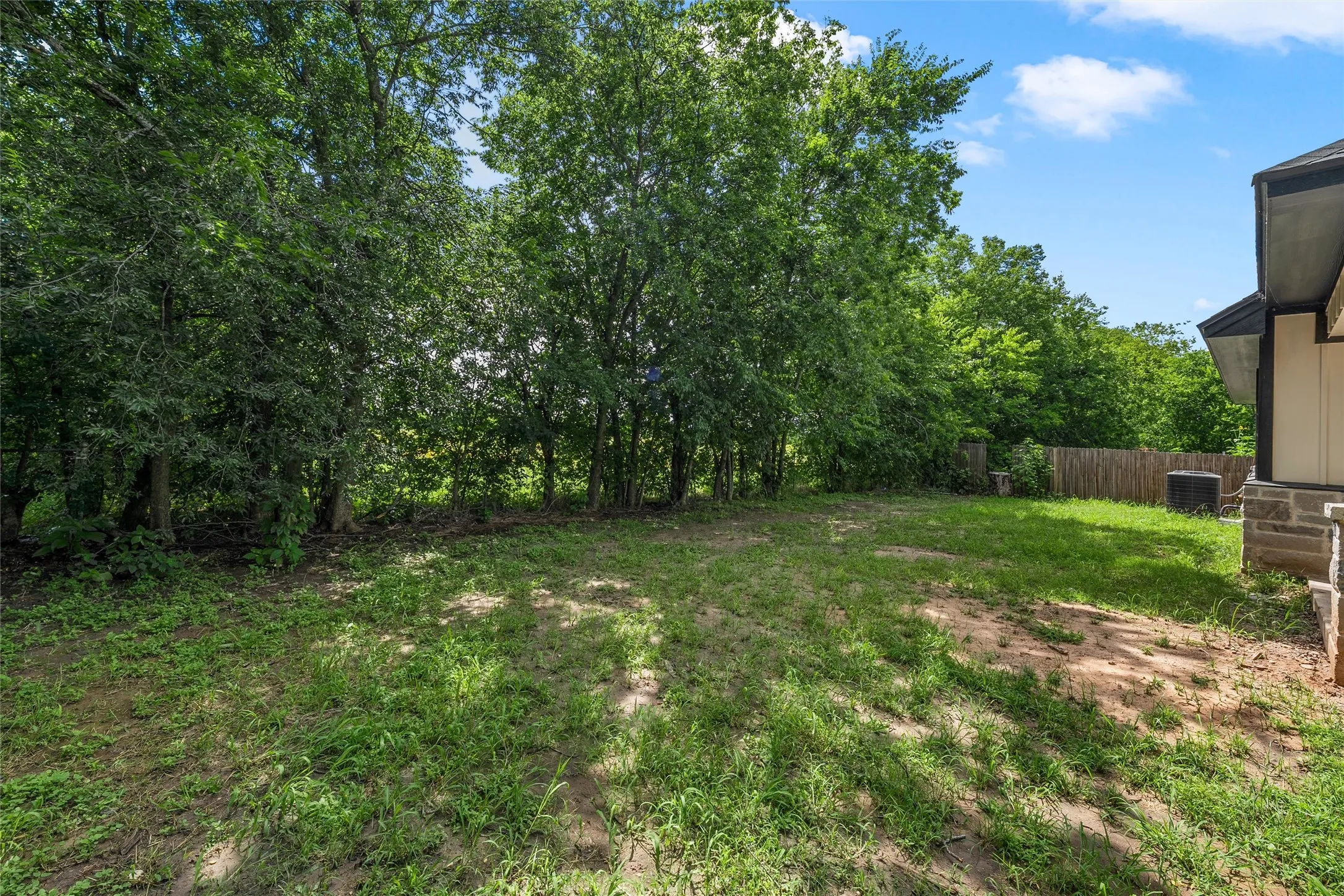Expansive rear yard featuring mature trees along the perimeter and a partial privacy fence