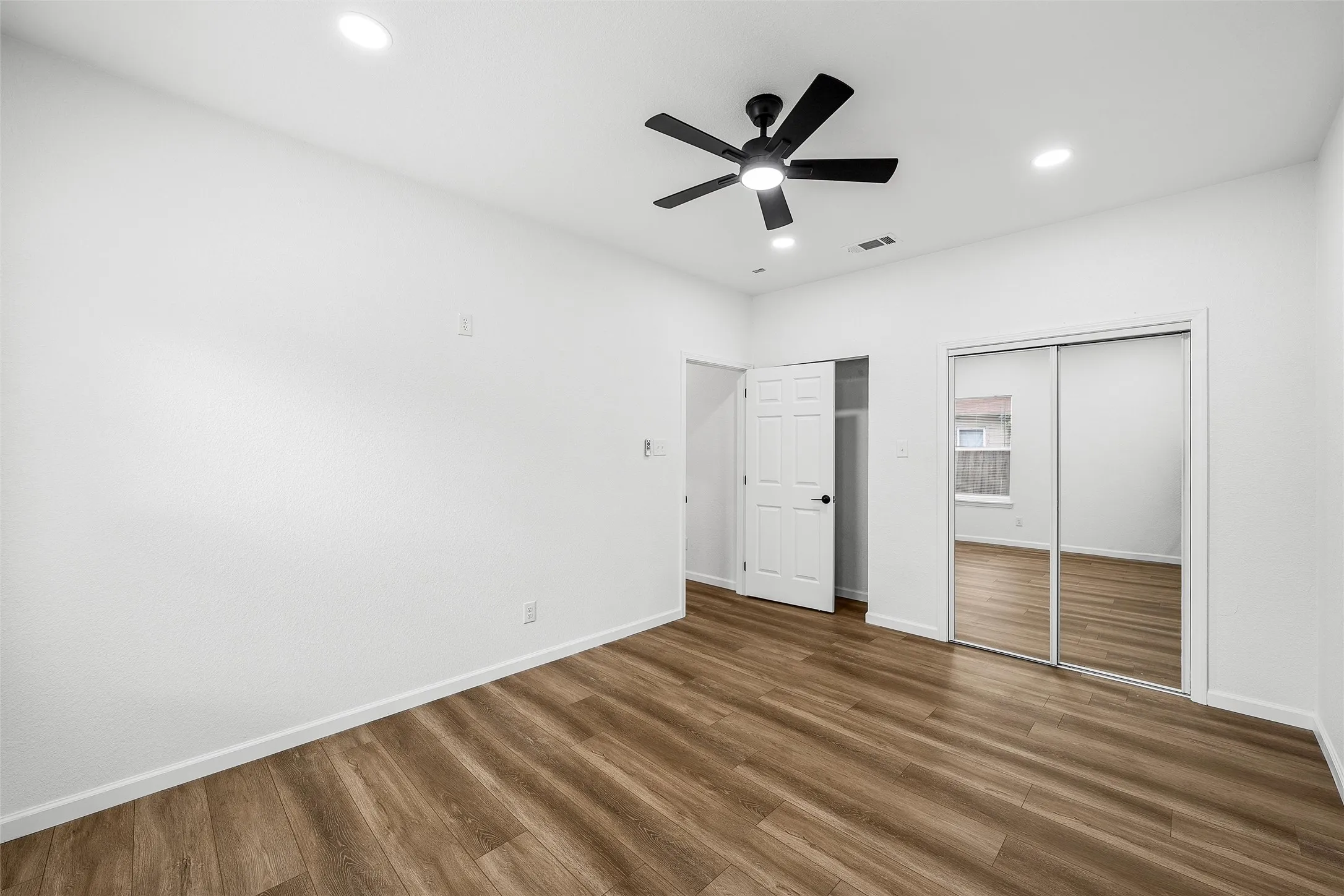 Bright room featuring wood-finish flooring, recessed lighting, and a ceiling fan