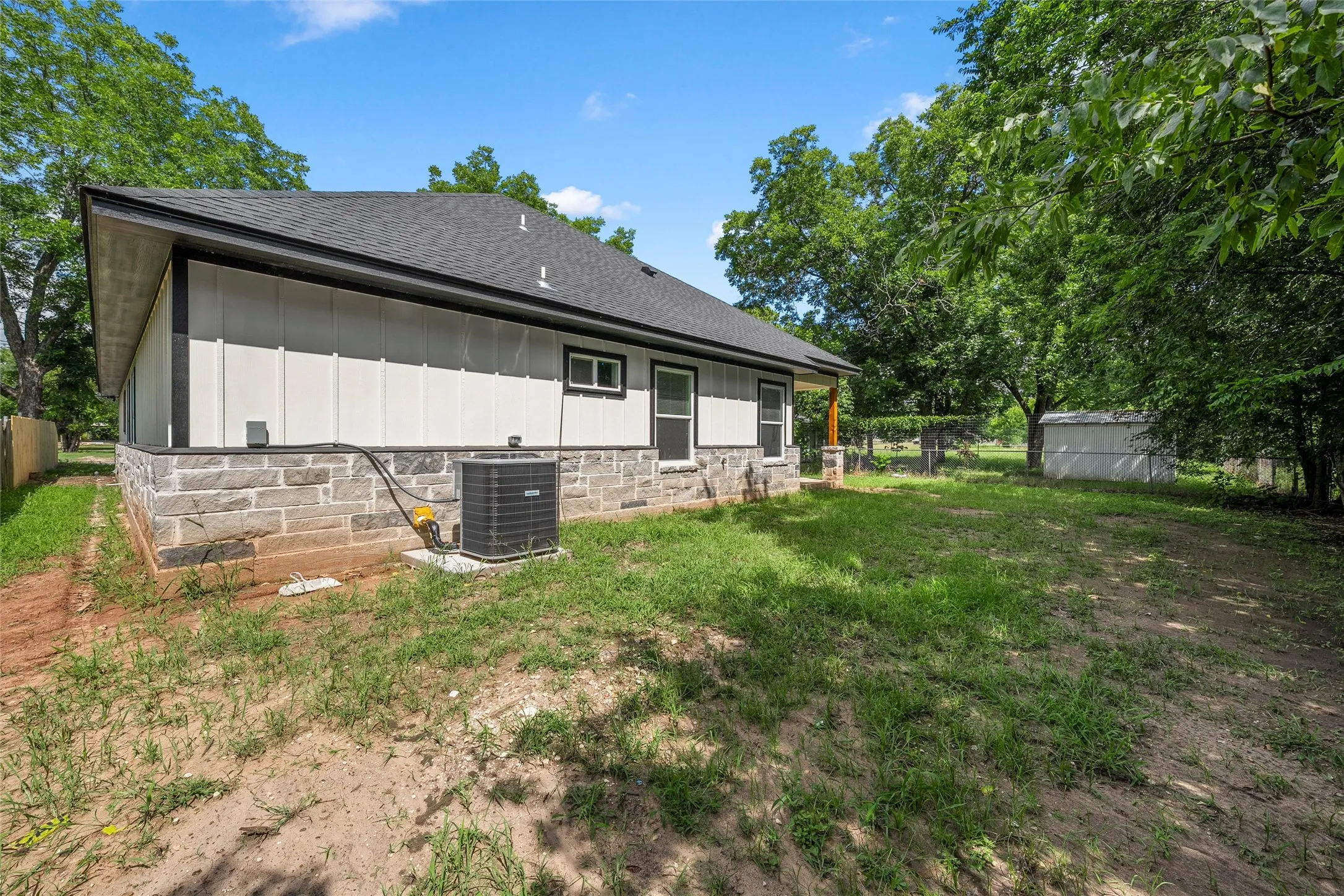 Exterior facade featuring board and batten siding, stone veneer, and a dark shingle roof