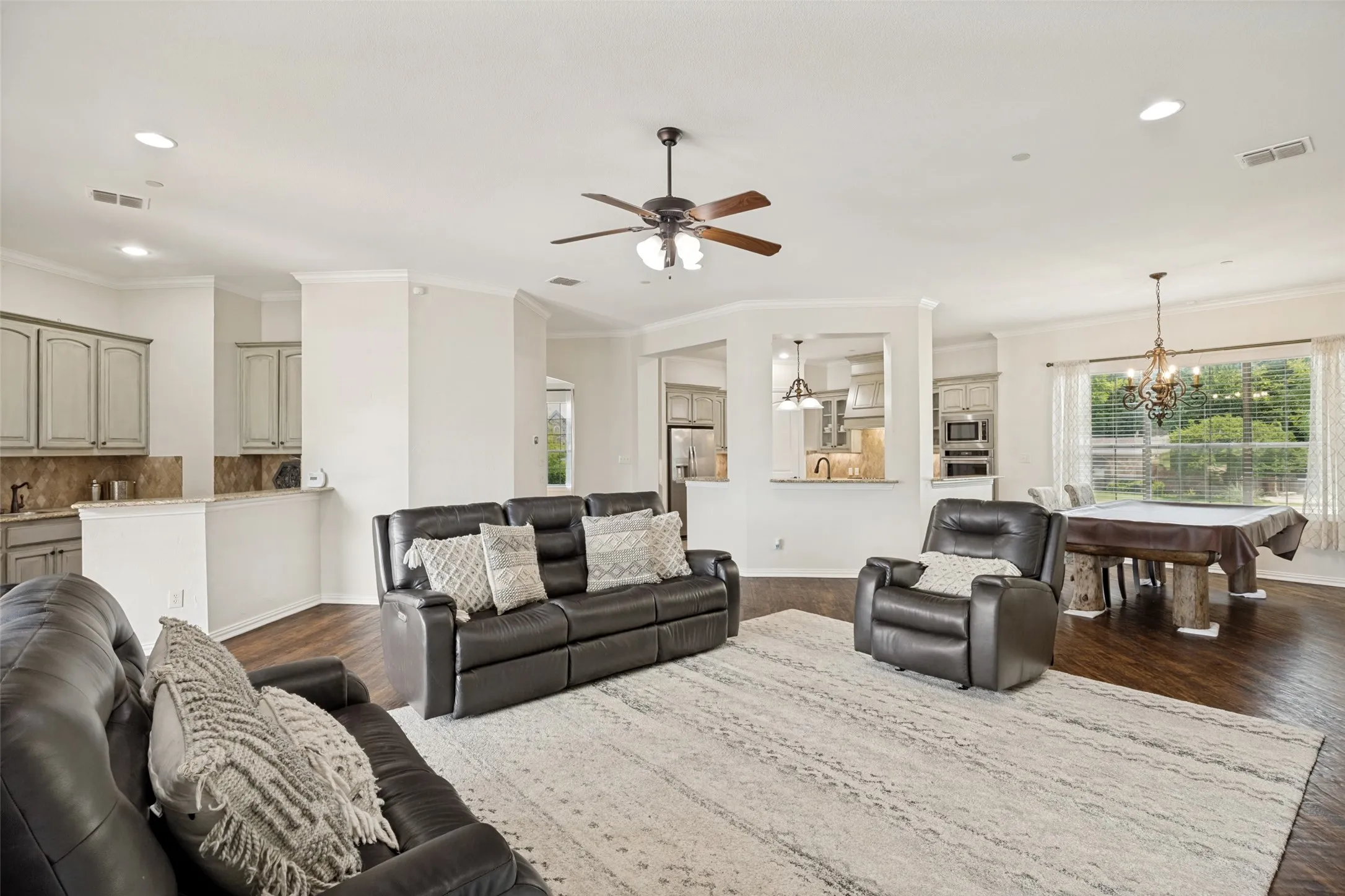 Spacious open-concept living area featuring wood-finish flooring, recessed lighting, and a ceiling fan