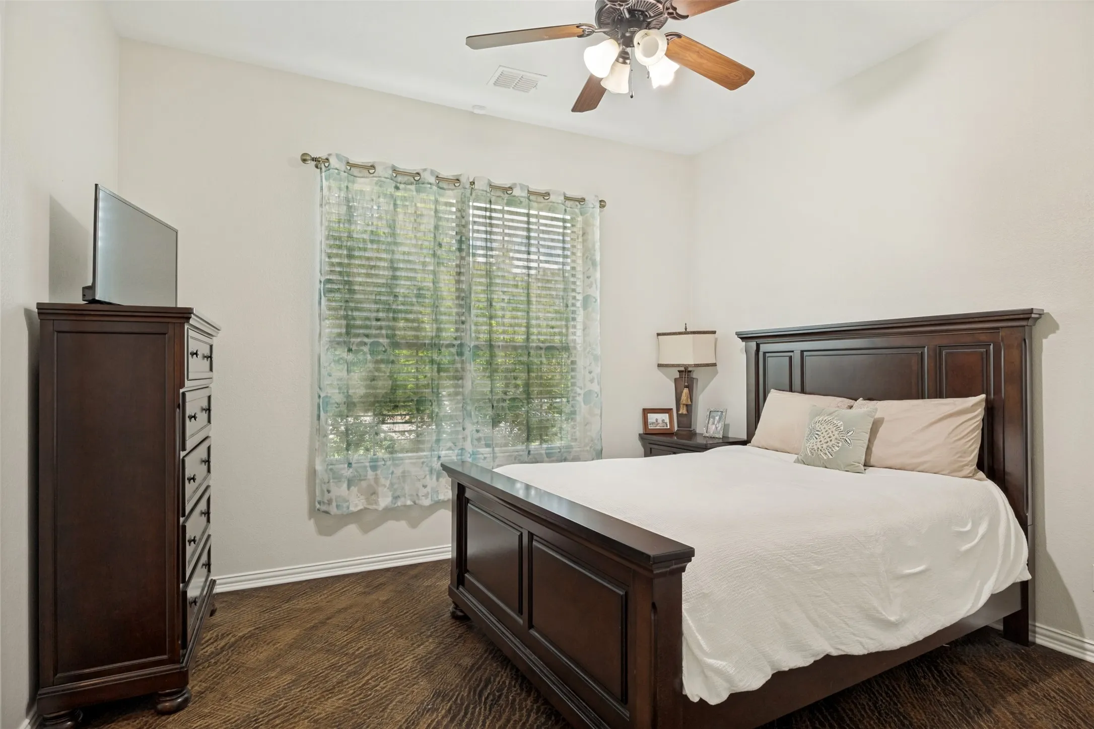 Bedroom featuring wood-finish flooring, a ceiling fan with integrated lighting, and a window with blinds