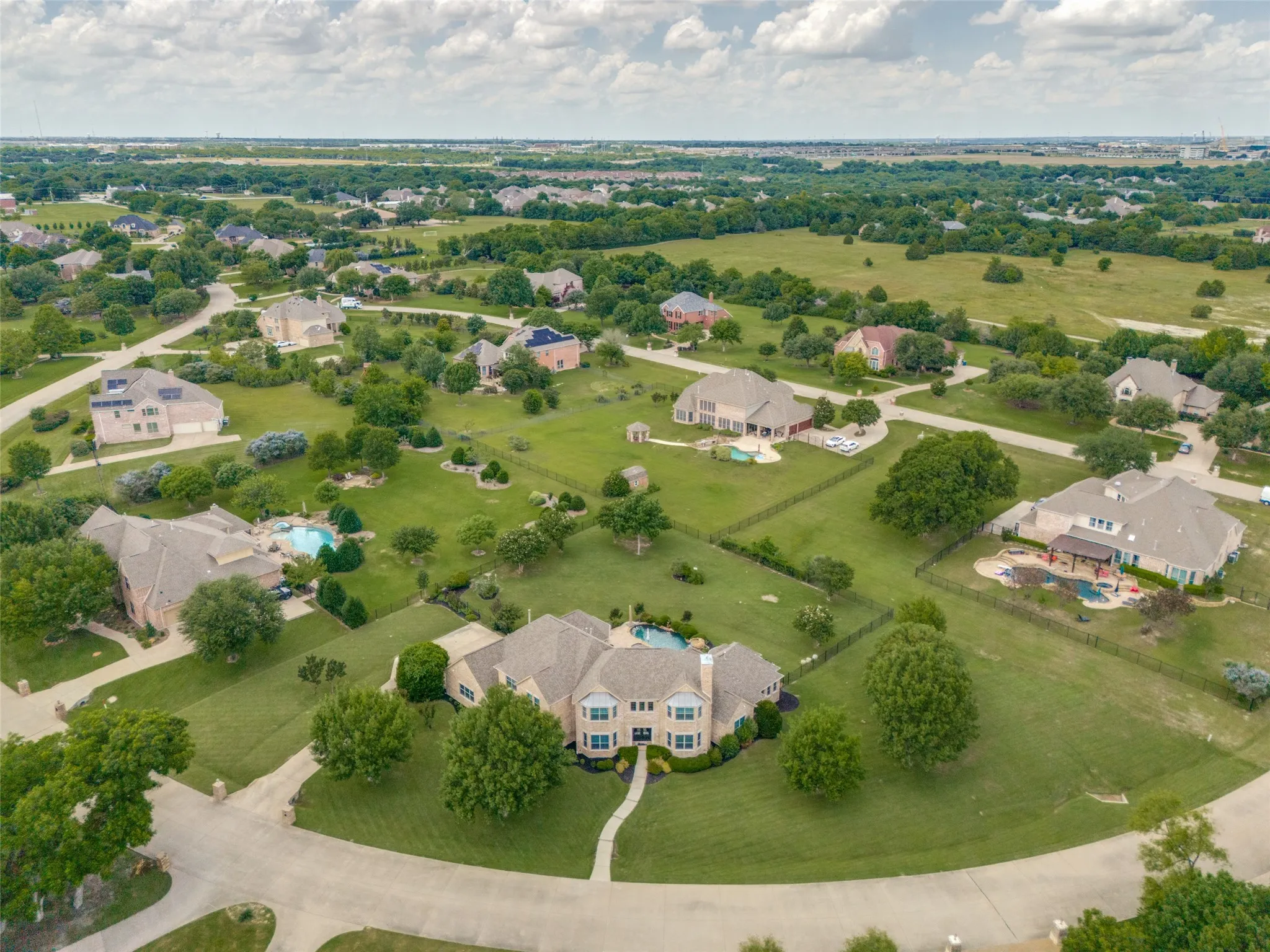 Spacious residential property featuring a large backyard with an in-ground swimming pool, extensive green lawn, mature trees, and a paved driveway leading to the front entrance