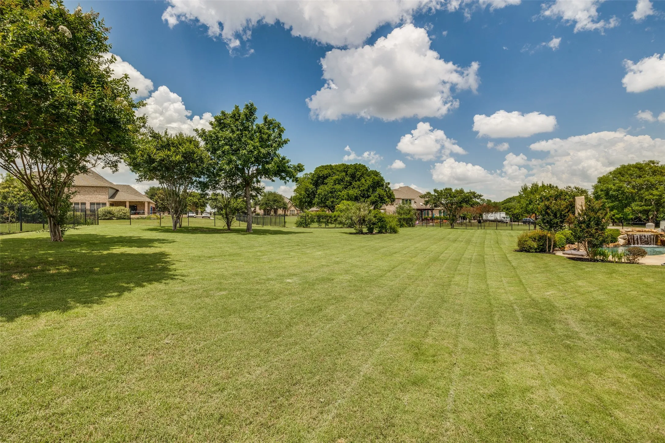 Expansive lawn featuring mature trees and established landscaping