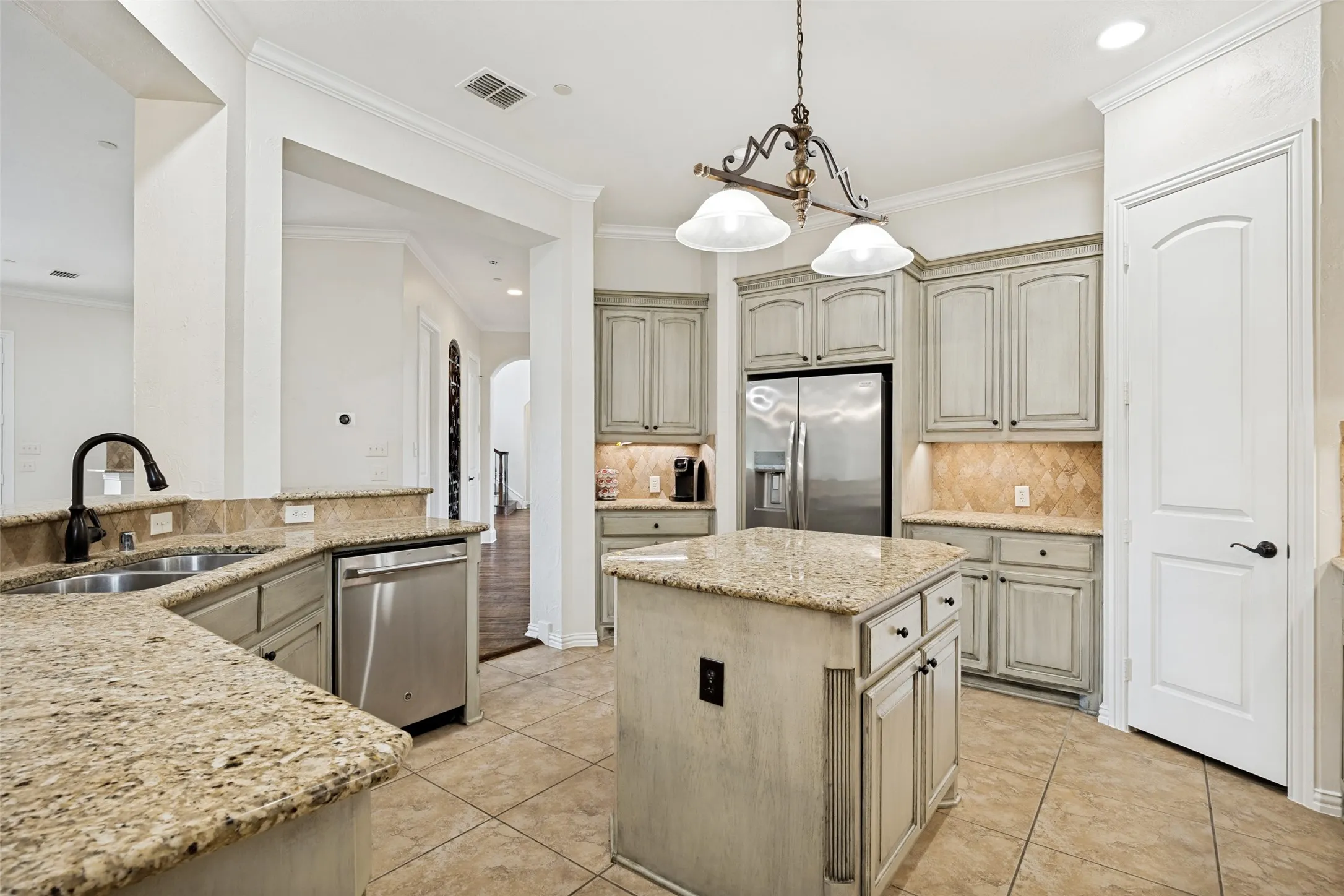 Kitchen featuring a central island with countertop, distressed cabinetry, stainless steel appliances, and a tile backsplash