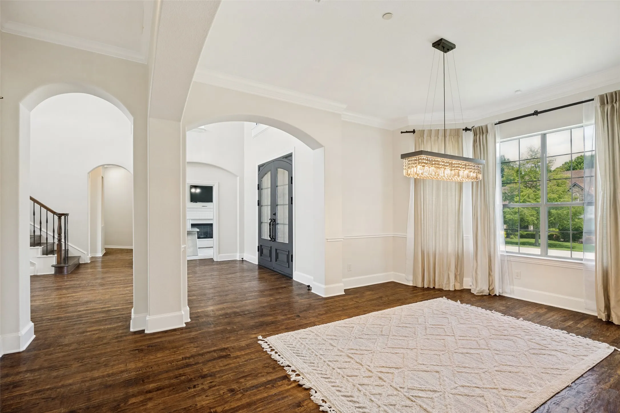 Expansive room featuring wood-finish flooring, a contemporary rectangular crystal chandelier, and large pane windows
