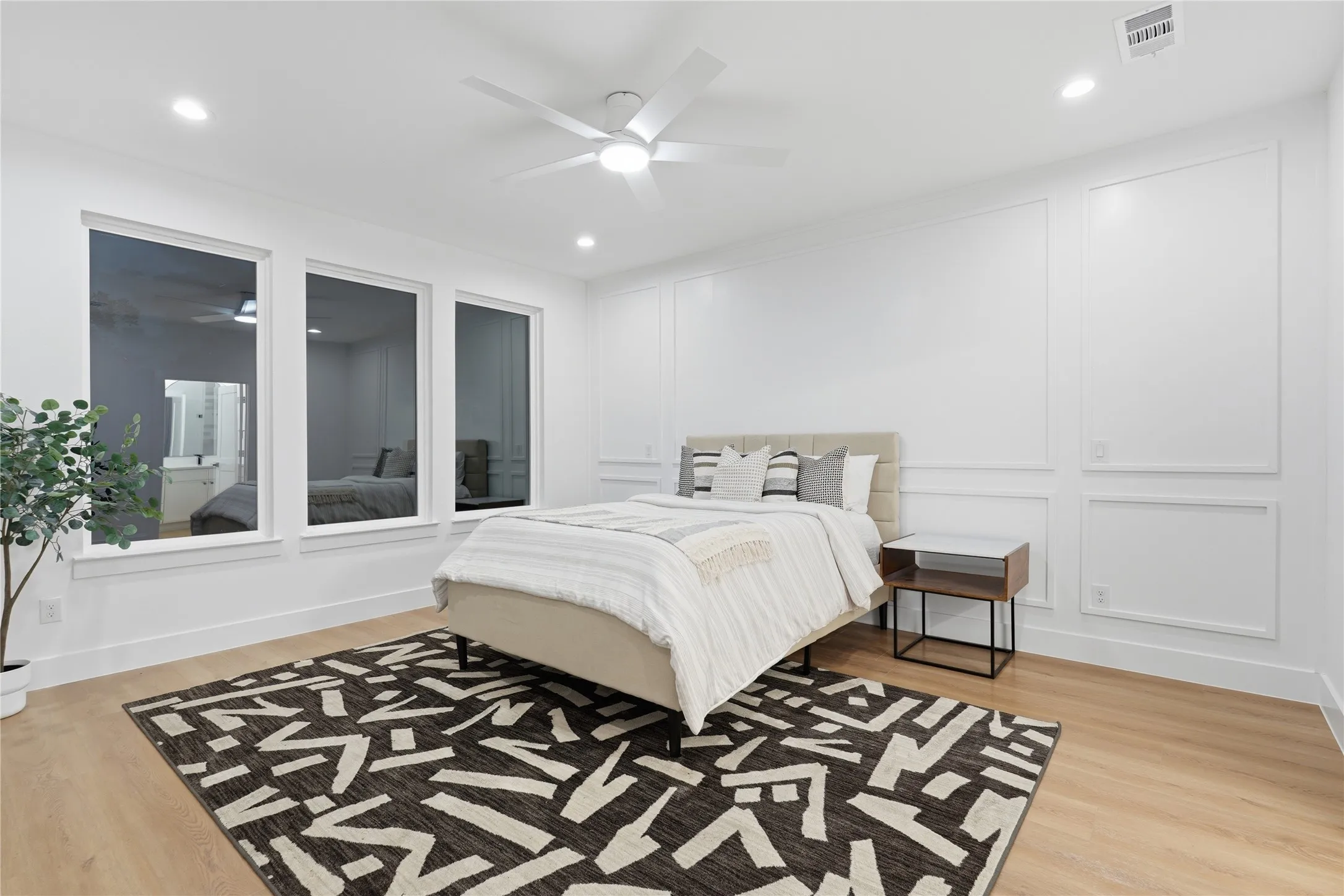 Spacious room featuring three large windows, wood-finish flooring, and recessed lighting