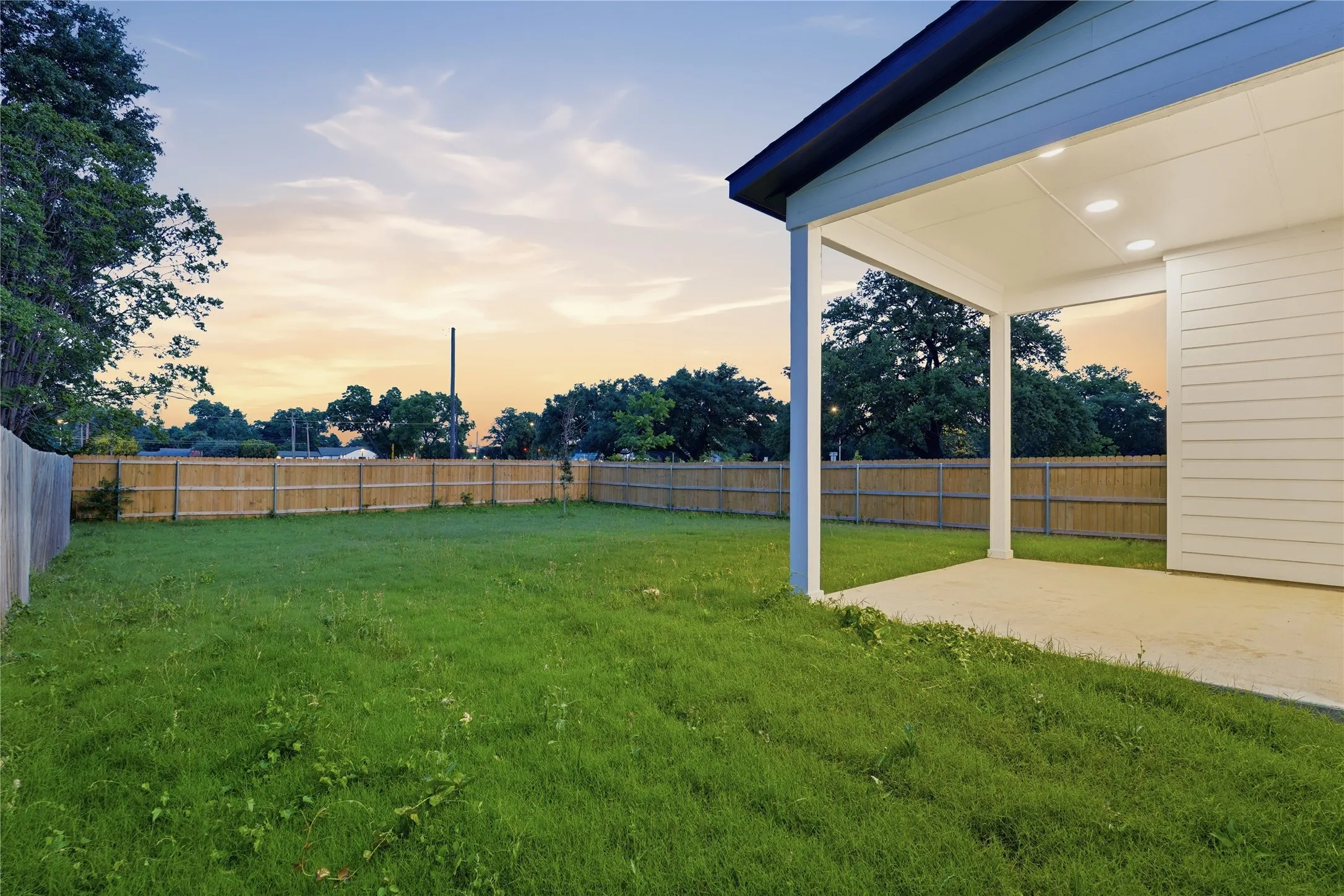 Expansive backyard featuring a manicured lawn, full privacy fencing, and mature perimeter trees