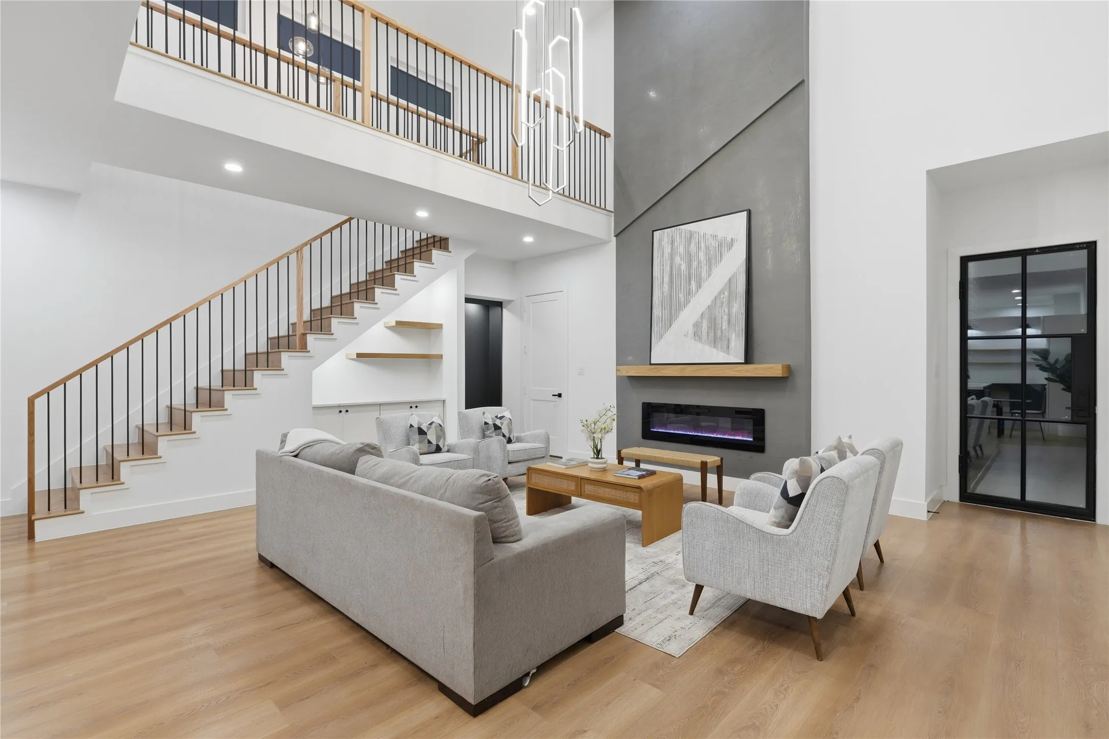 Double-height living space featuring wood-finish flooring and a contemporary linear fireplace
