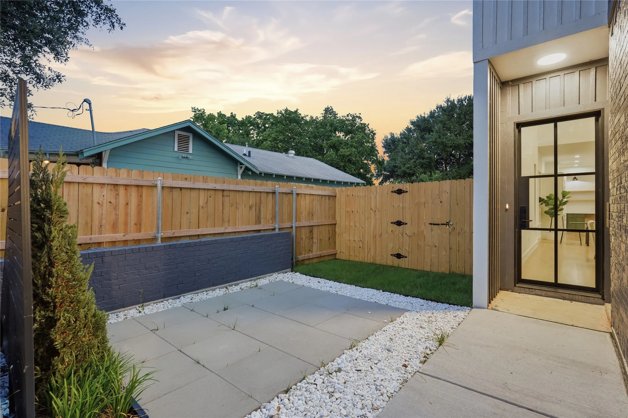 Modern entry door with black grid design, featuring a concrete pathway and white decorative gravel