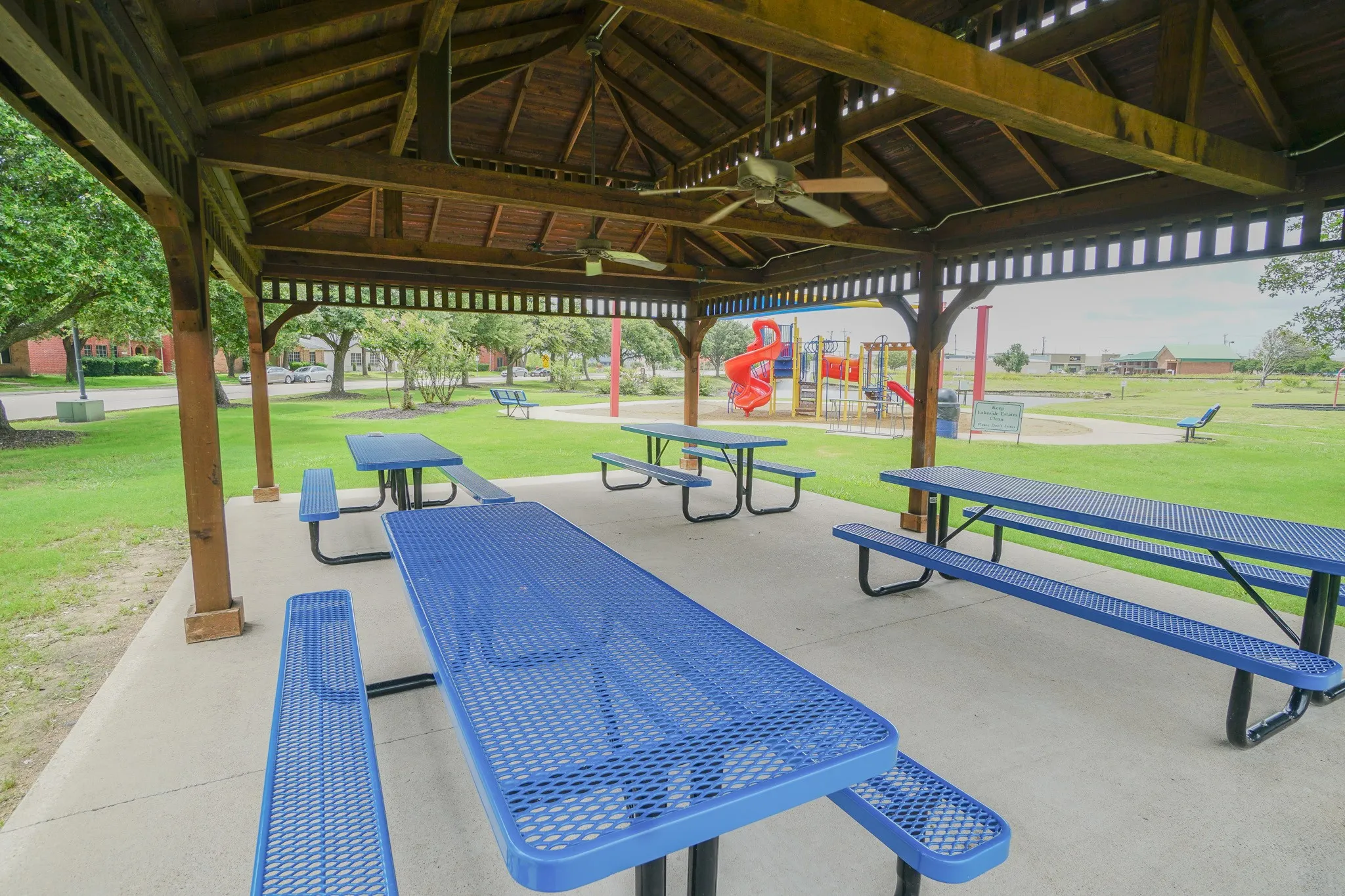 Spacious wooden gazebo featuring a slatted roof and concrete flooring