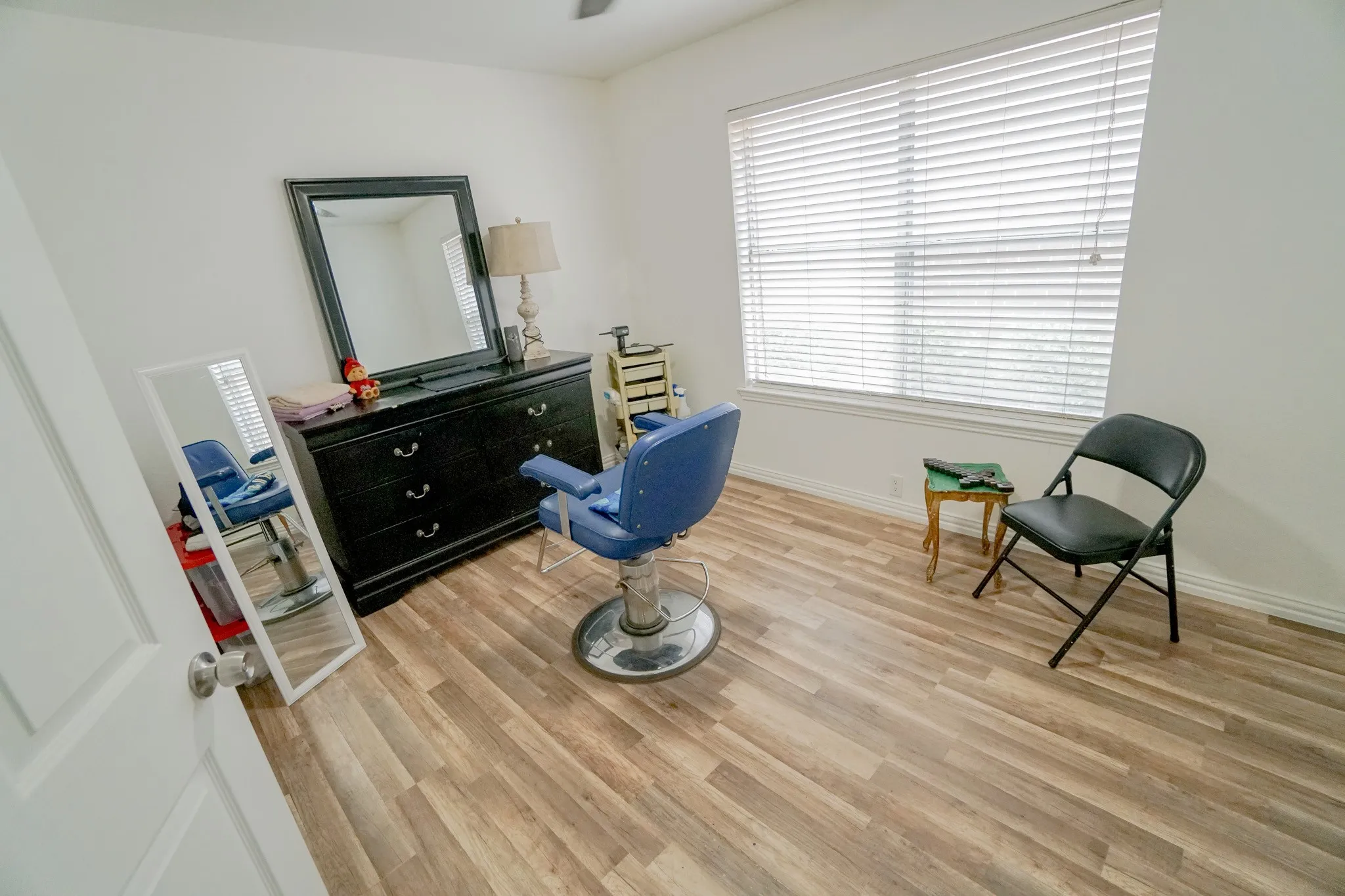 Bright room featuring wood-finish flooring, white walls, and a large window with blinds