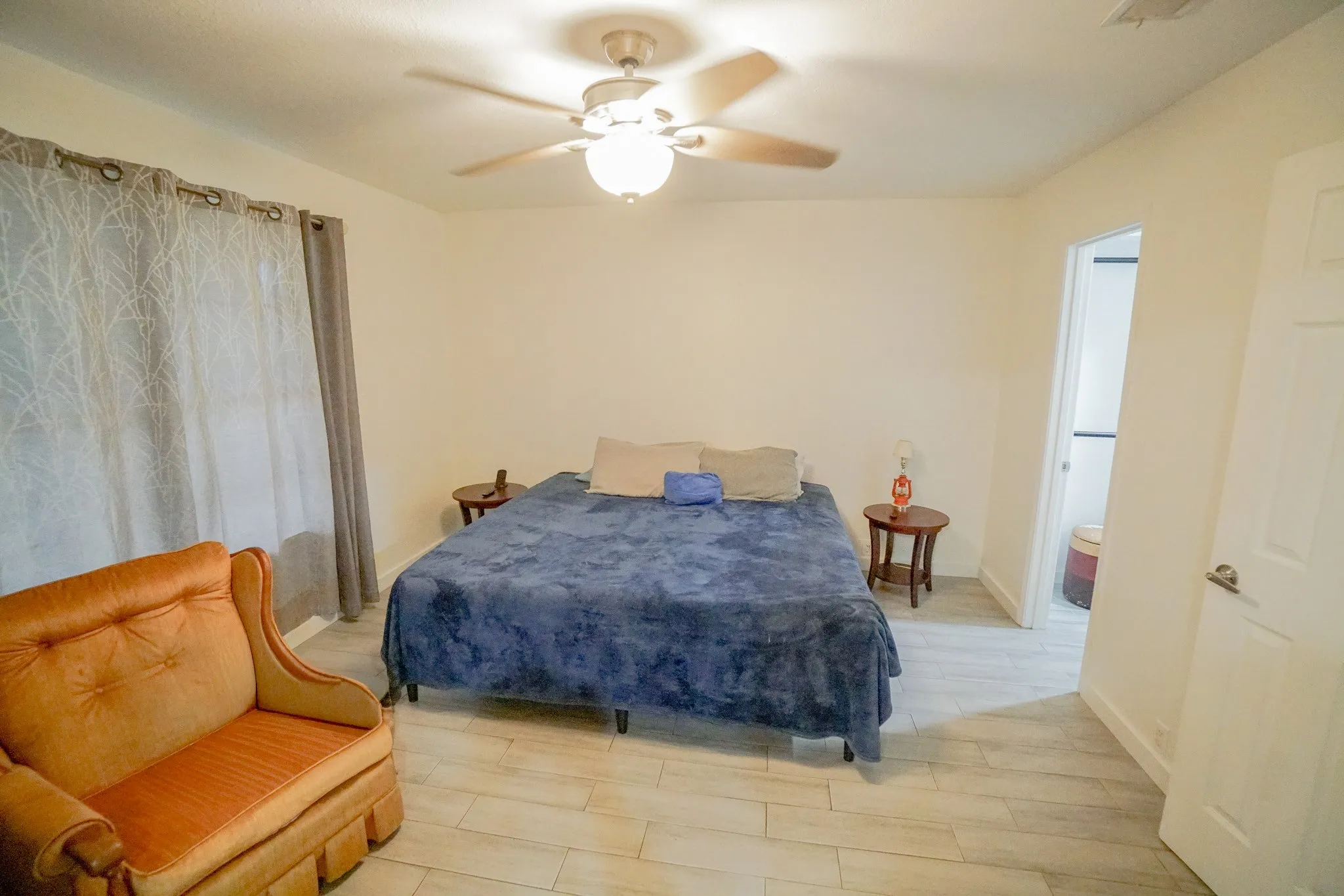 Spacious room featuring light wood-finish flooring, a ceiling fan with integrated lighting, and neutral wall tones