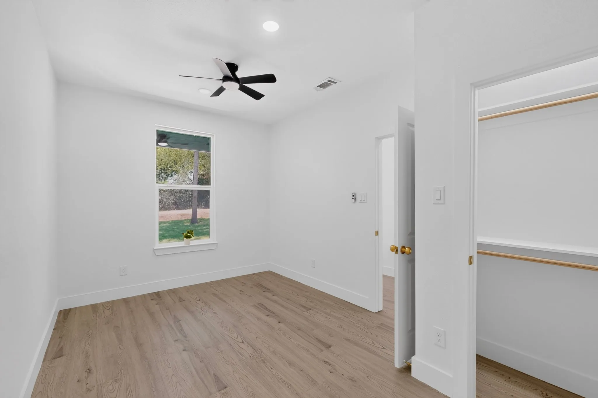 Room featuring wood-finish flooring, a ceiling fan with integrated lighting, recessed overhead lighting, and a window with exterior tree scenery