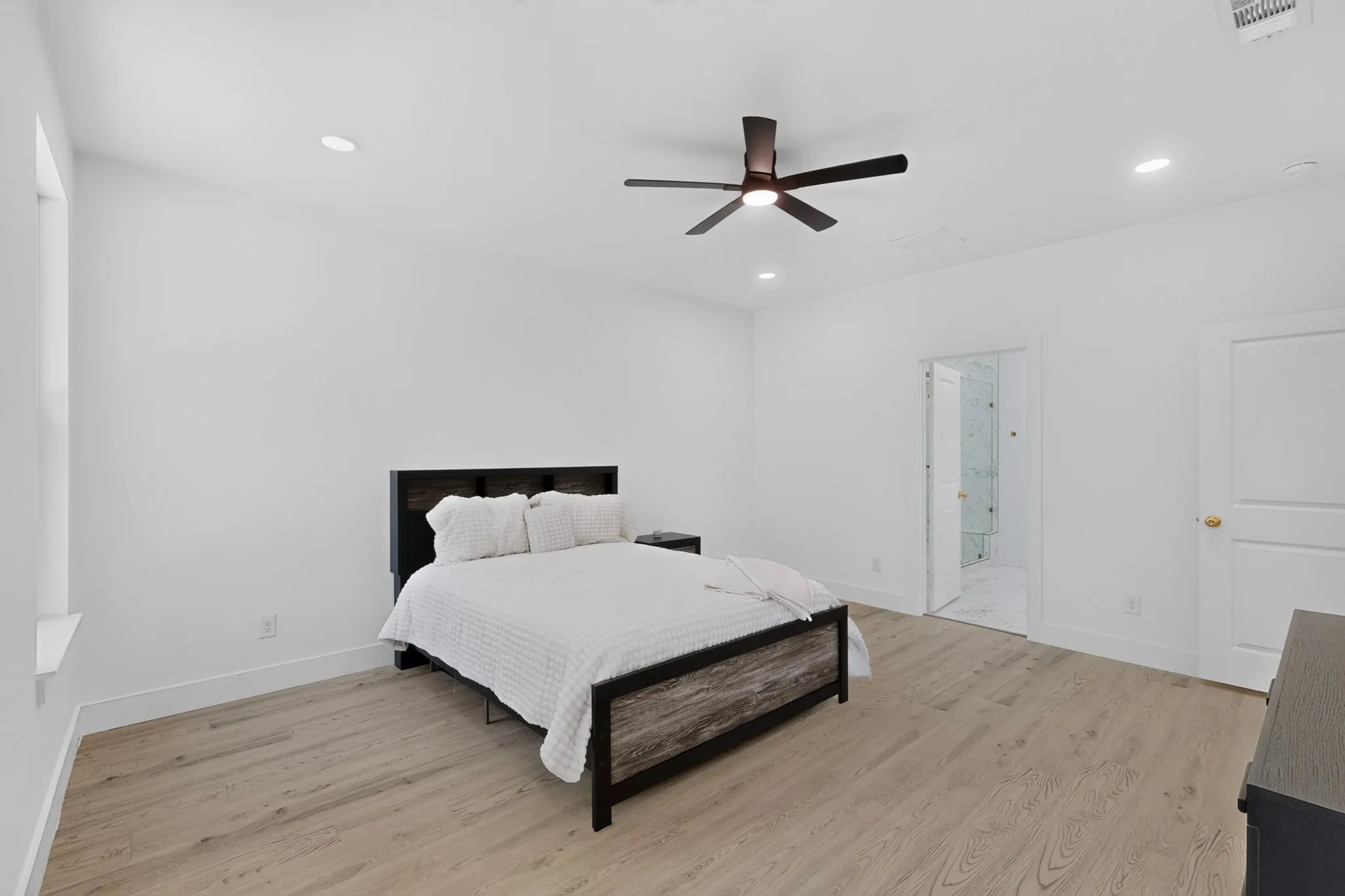 Bedroom featuring light wood-finish flooring, recessed lighting, and a dark-toned ceiling fan