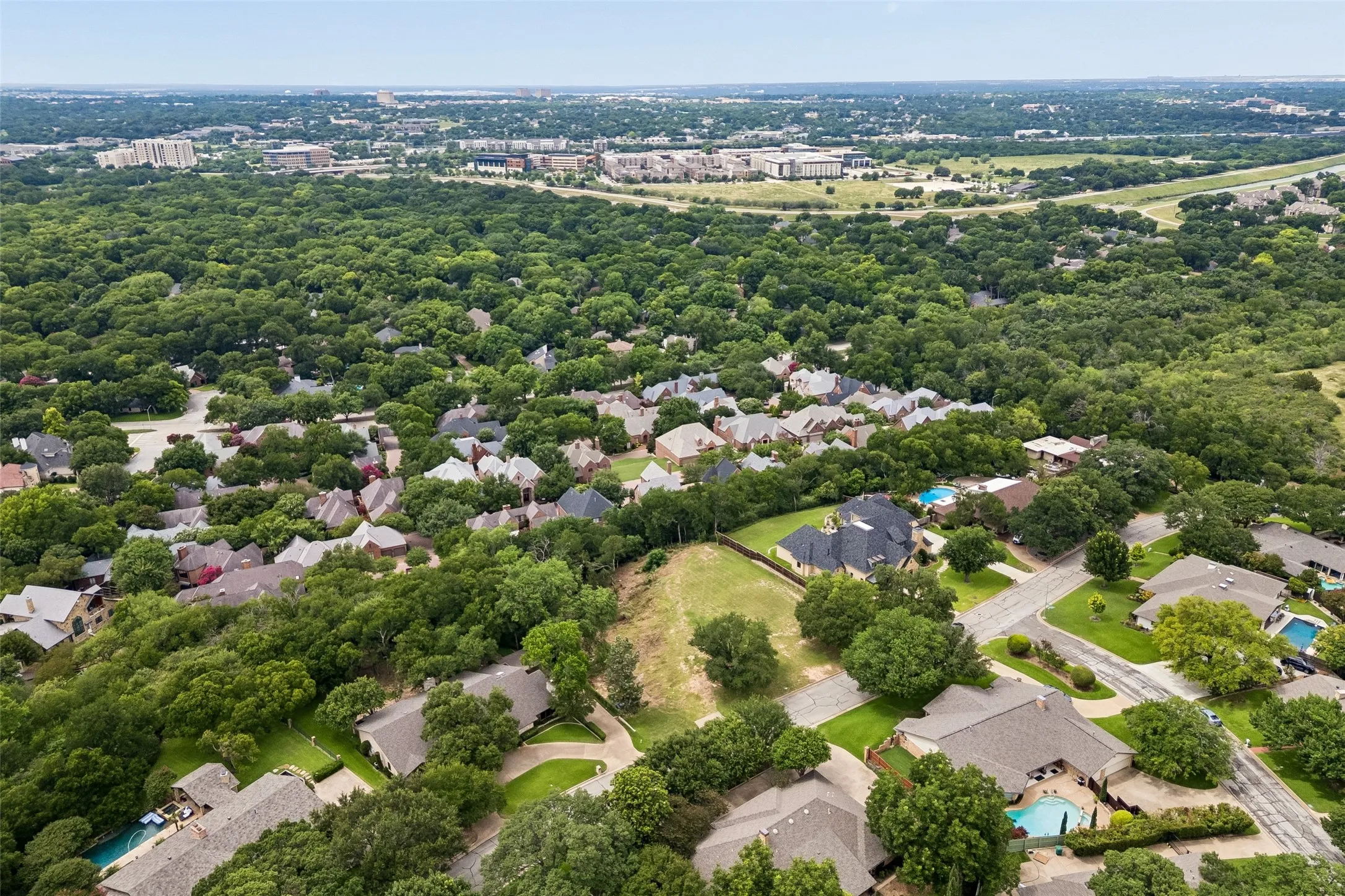 Wide aerial perspective highlighting the lot’s placement among established homes, mature trees, and nearby area amenities.