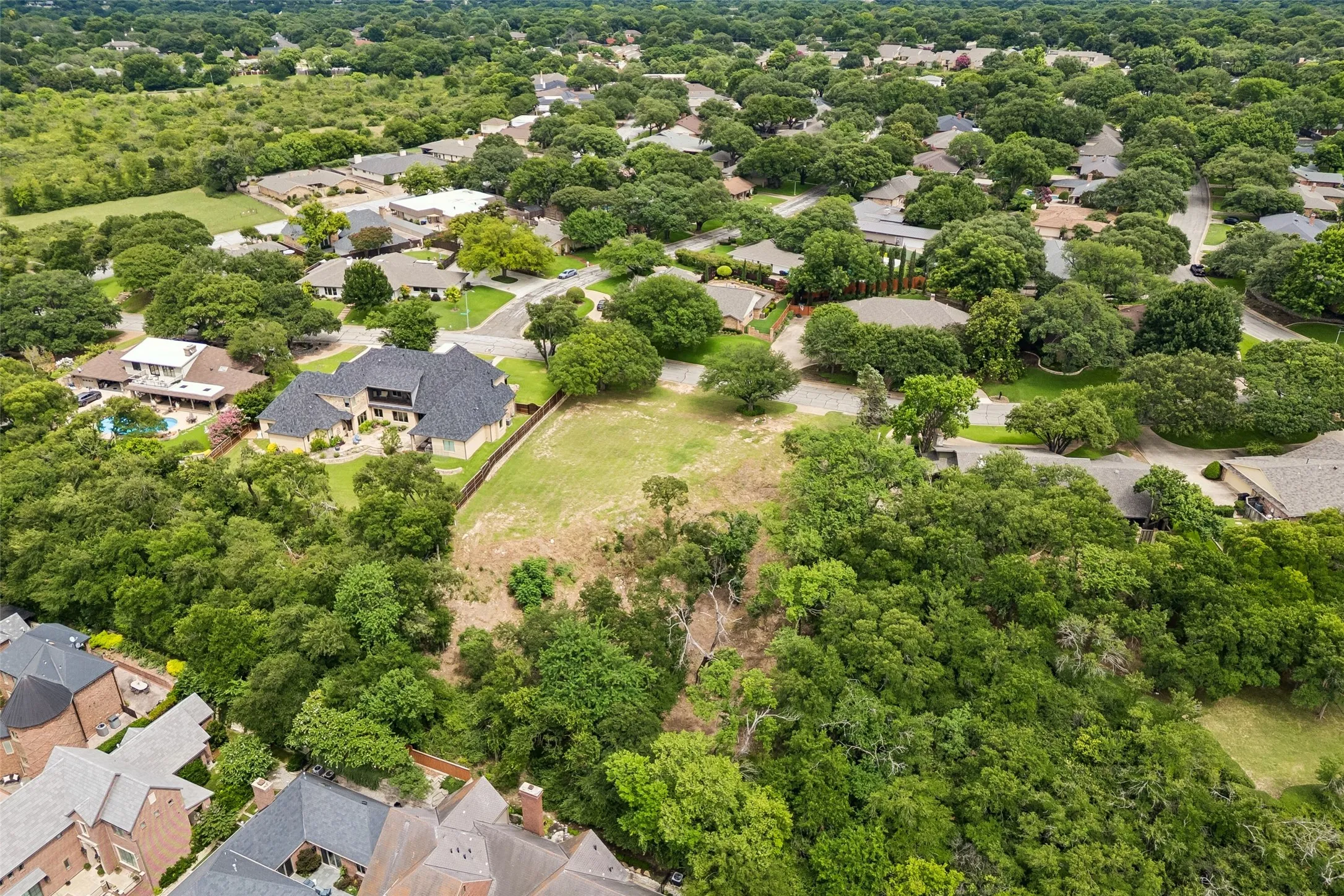 Expansive build area with mature trees, neighboring estate homes, and views extending beyond the property.