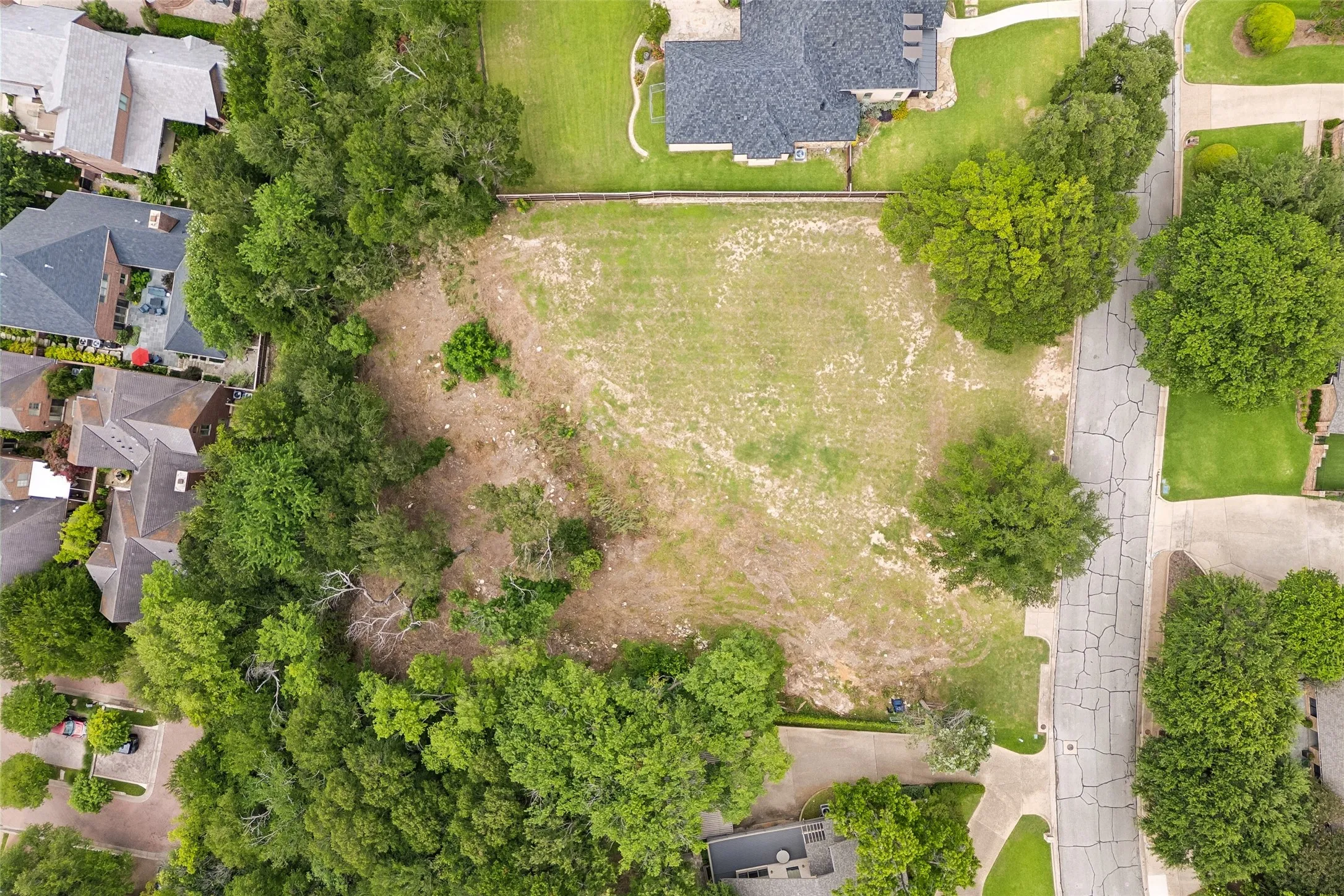 Overhead aerial view showing the open/prepped build area, mature trees, street frontage, and overall lot configuration.