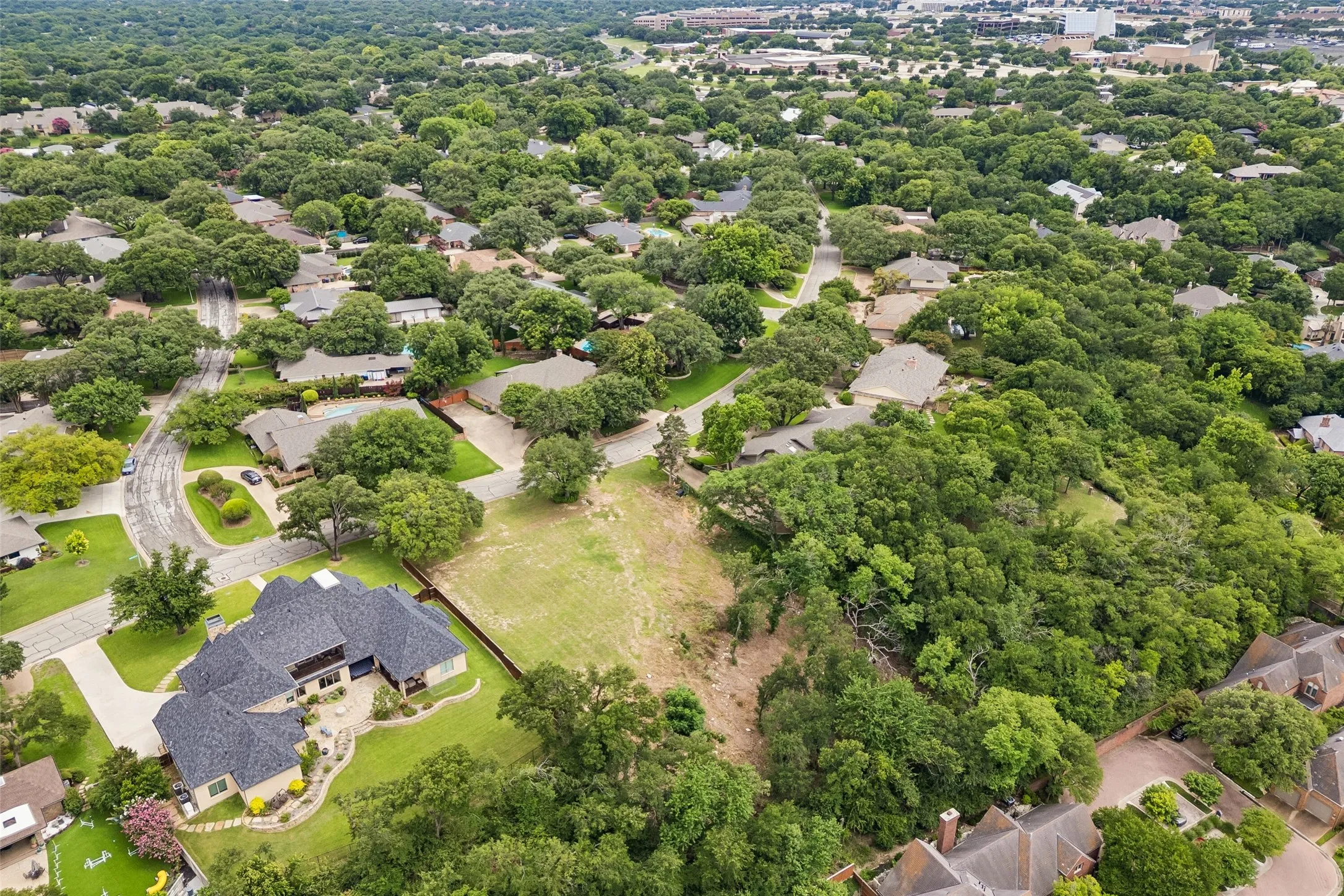 Aerial view of the 1.036-acre Overton West homesite, showcasing the elevated setting, mature tree canopy, and surrounding neighborhood context.