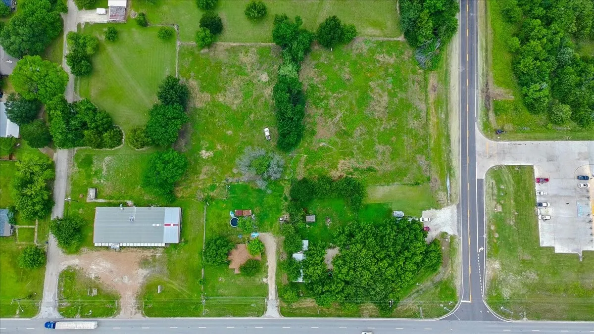Expansive property featuring a large commercial-style building with a gray roof and multiple adjacent parcels of open land