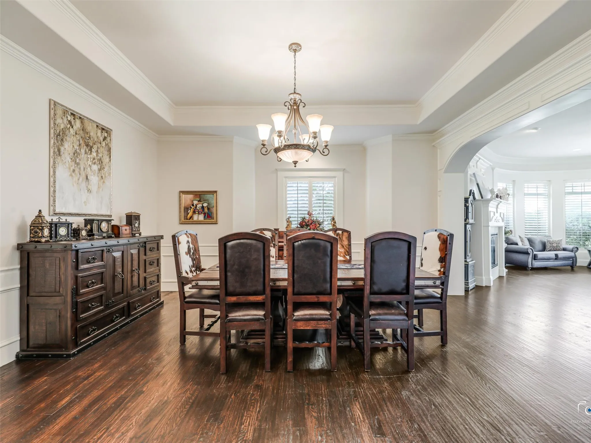 Formal dining area featuring rich wood-finish flooring, a tray ceiling, and an ornate chandelier