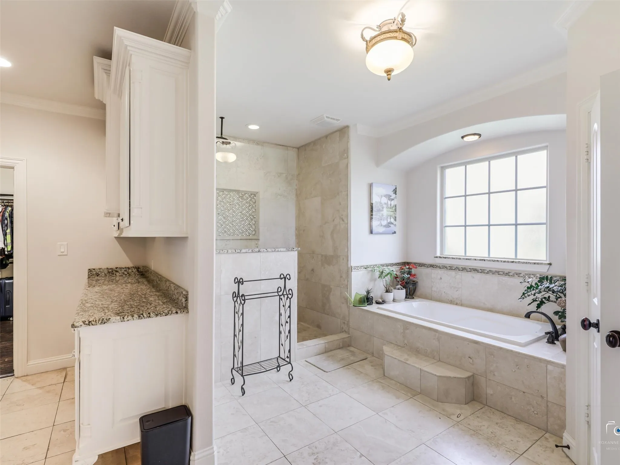 Bathroom featuring a built-in tub with tile surround, a separate tiled shower, and a window with grid detailing