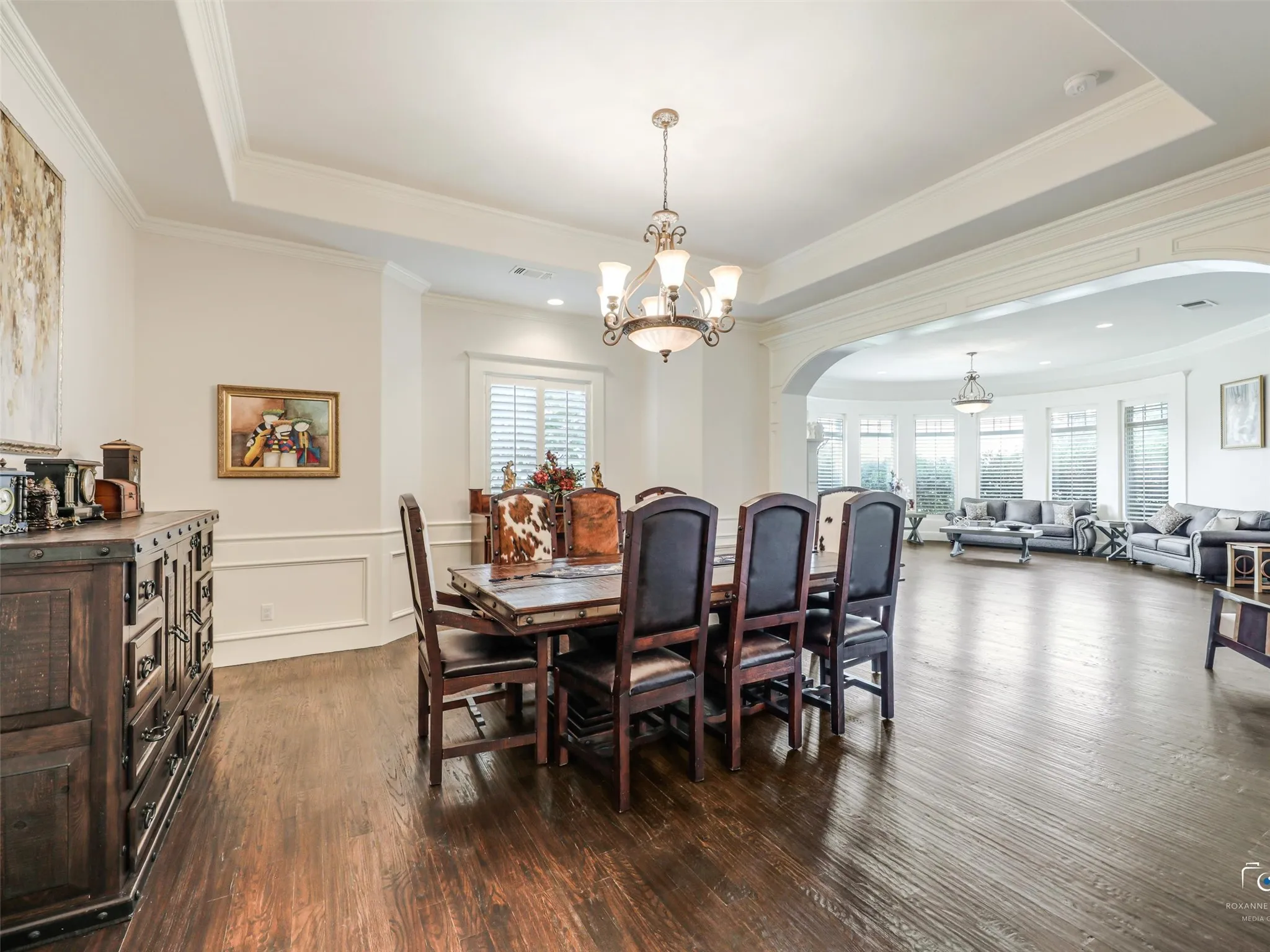 Rich wood-finish flooring extends through this room, featuring decorative wainscoting and a tray ceiling