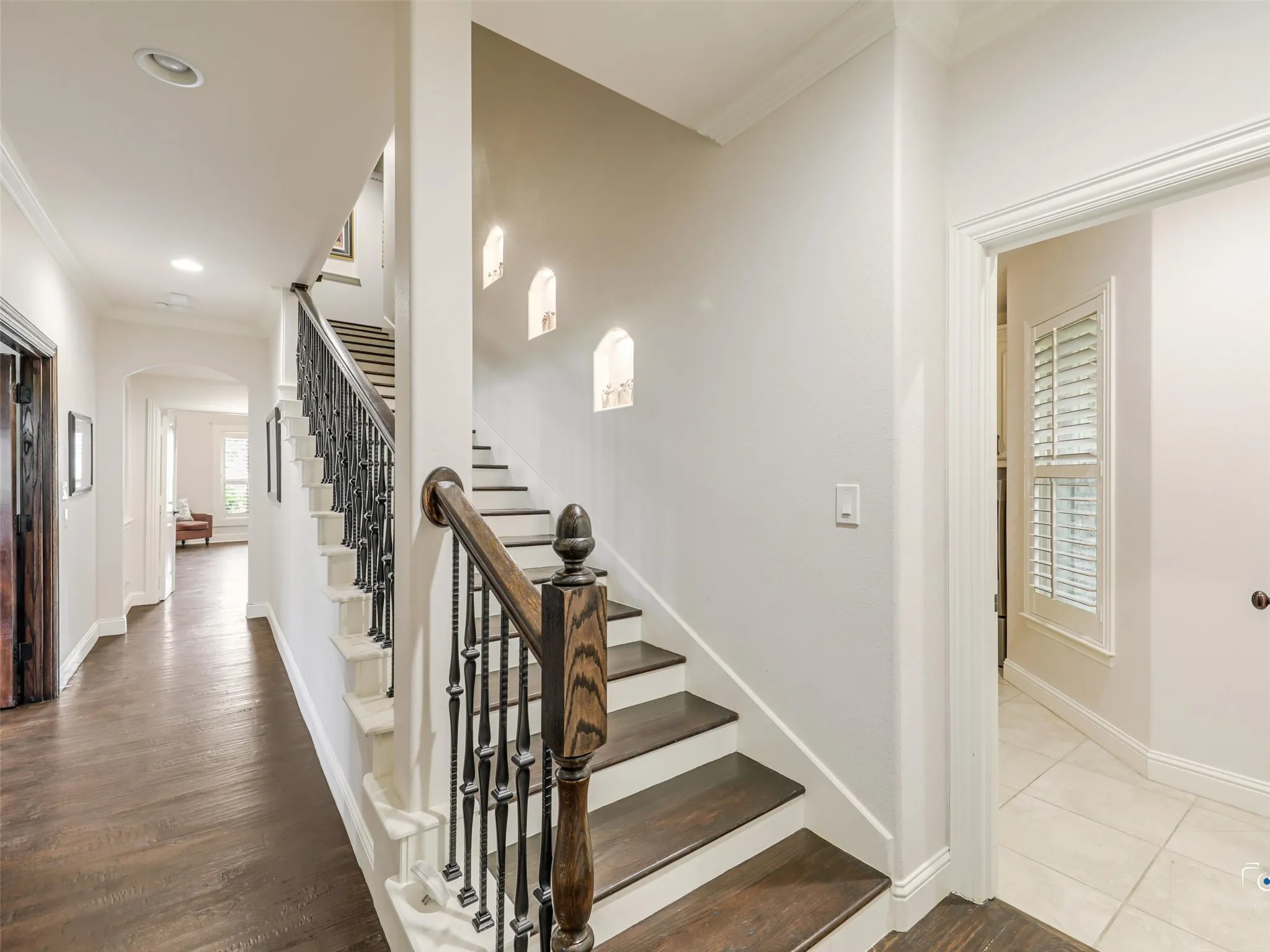 Staircase featuring dark wood-finish treads, white risers, and wrought iron balusters with a wood-finish handrail
