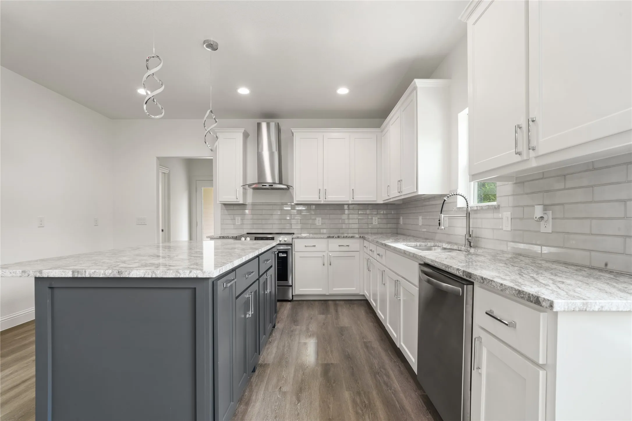 Modern kitchen featuring a contrasting island with granite-style countertops, white cabinetry, a subway tile backsplash, stainless steel appliances, and wood-finish flooring