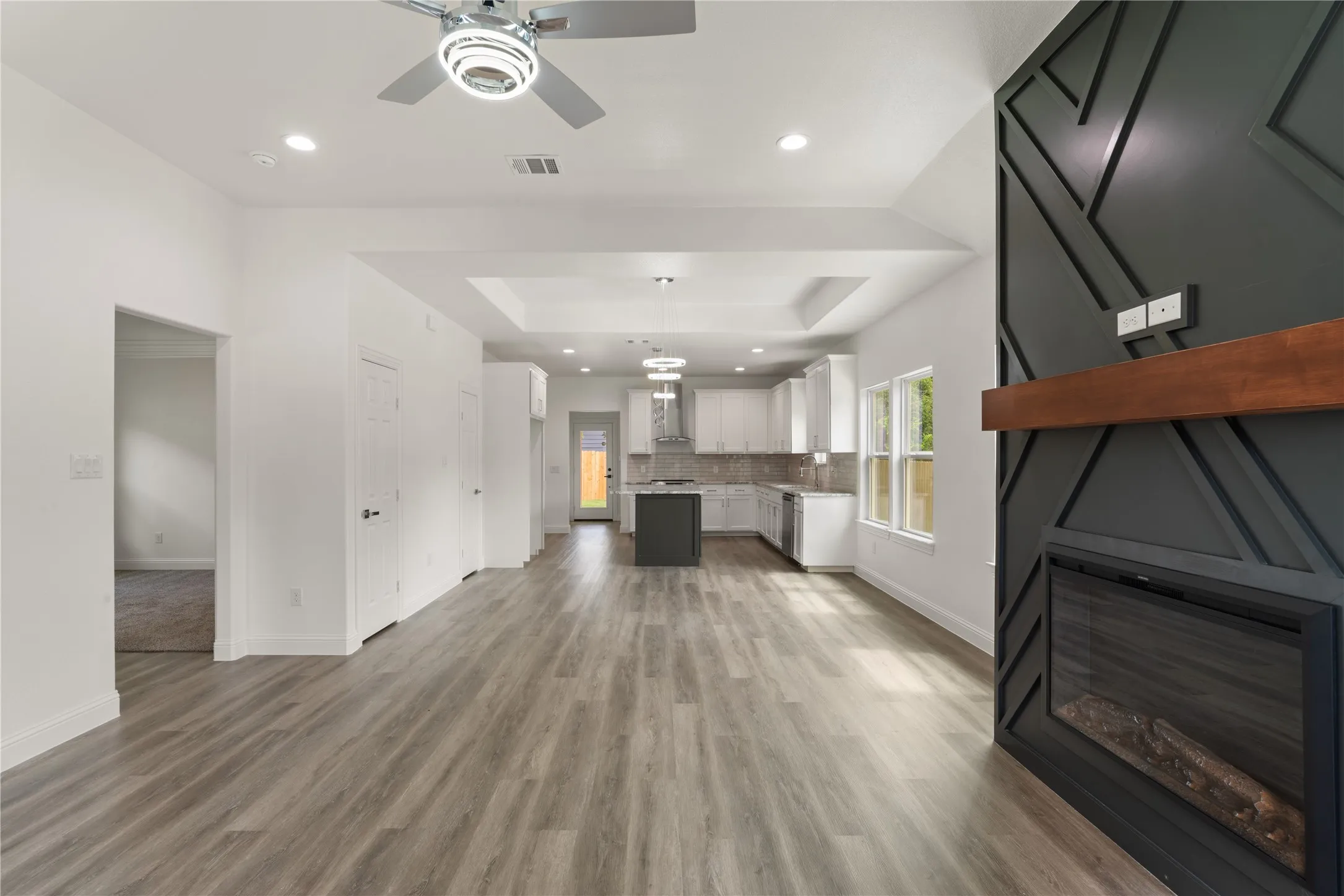 Spacious open-concept living area featuring wood-finish flooring, a contemporary ceiling fan, and recessed lighting