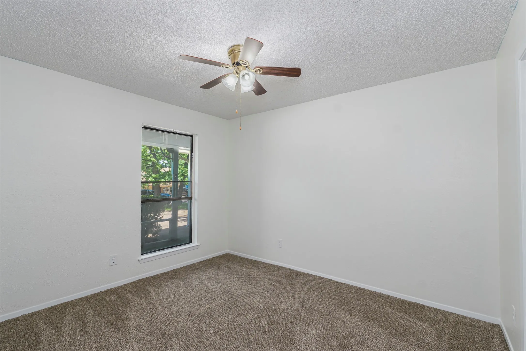Carpeted room featuring a ceiling fan with light fixture, a single window, and white baseboards