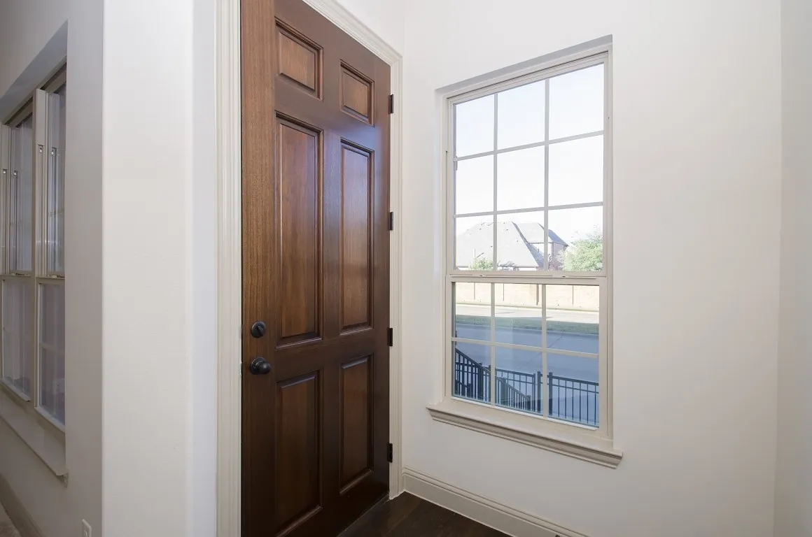 Rich wood-paneled entry door with dark hardware, framed by a grid-pattern window and a multi-pane window