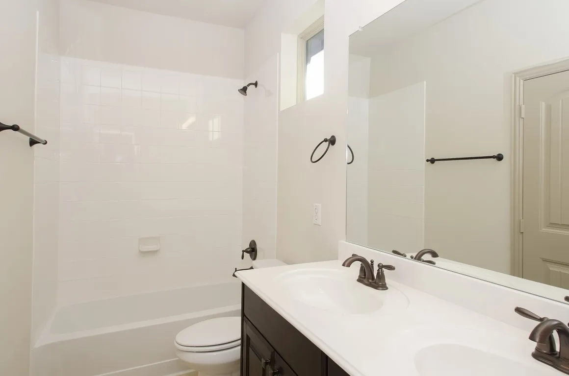 Bathroom featuring a dual-sink vanity with dark cabinetry, white countertops, and bronze-finish fixtures