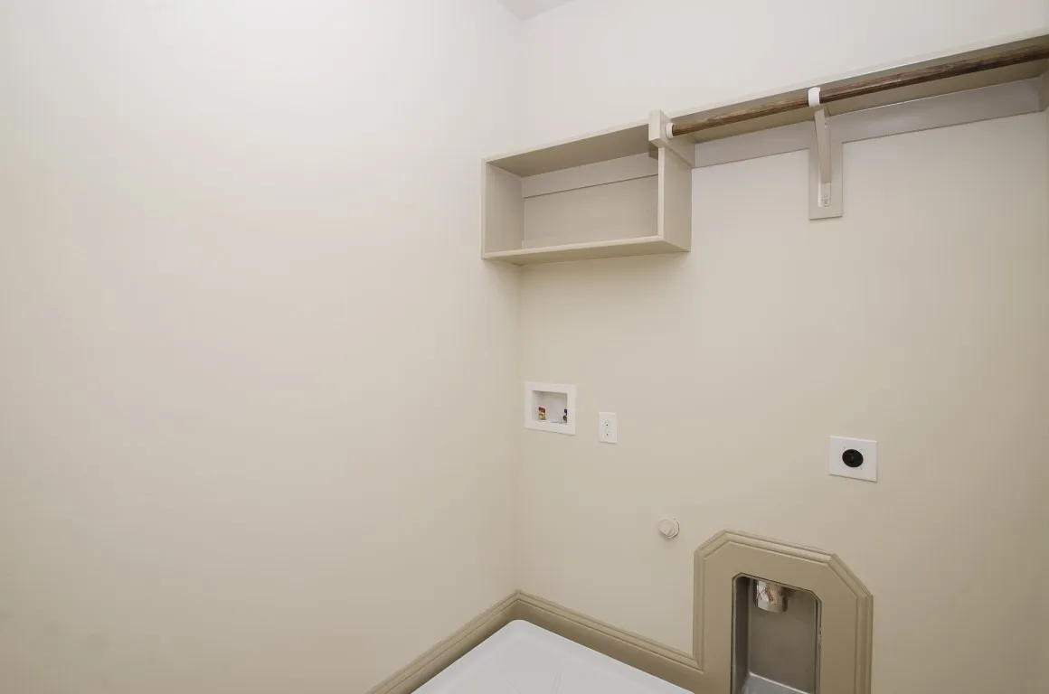 Dedicated utility area featuring a built-in shelf, garment hanging rod, and essential appliance hookups