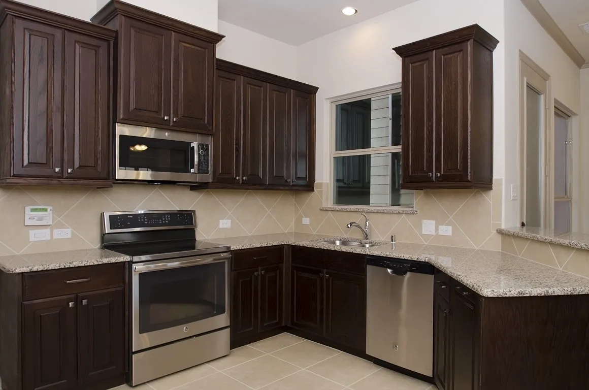 Kitchen featuring dark wood-finish cabinetry, light-toned countertops, and stainless steel appliances