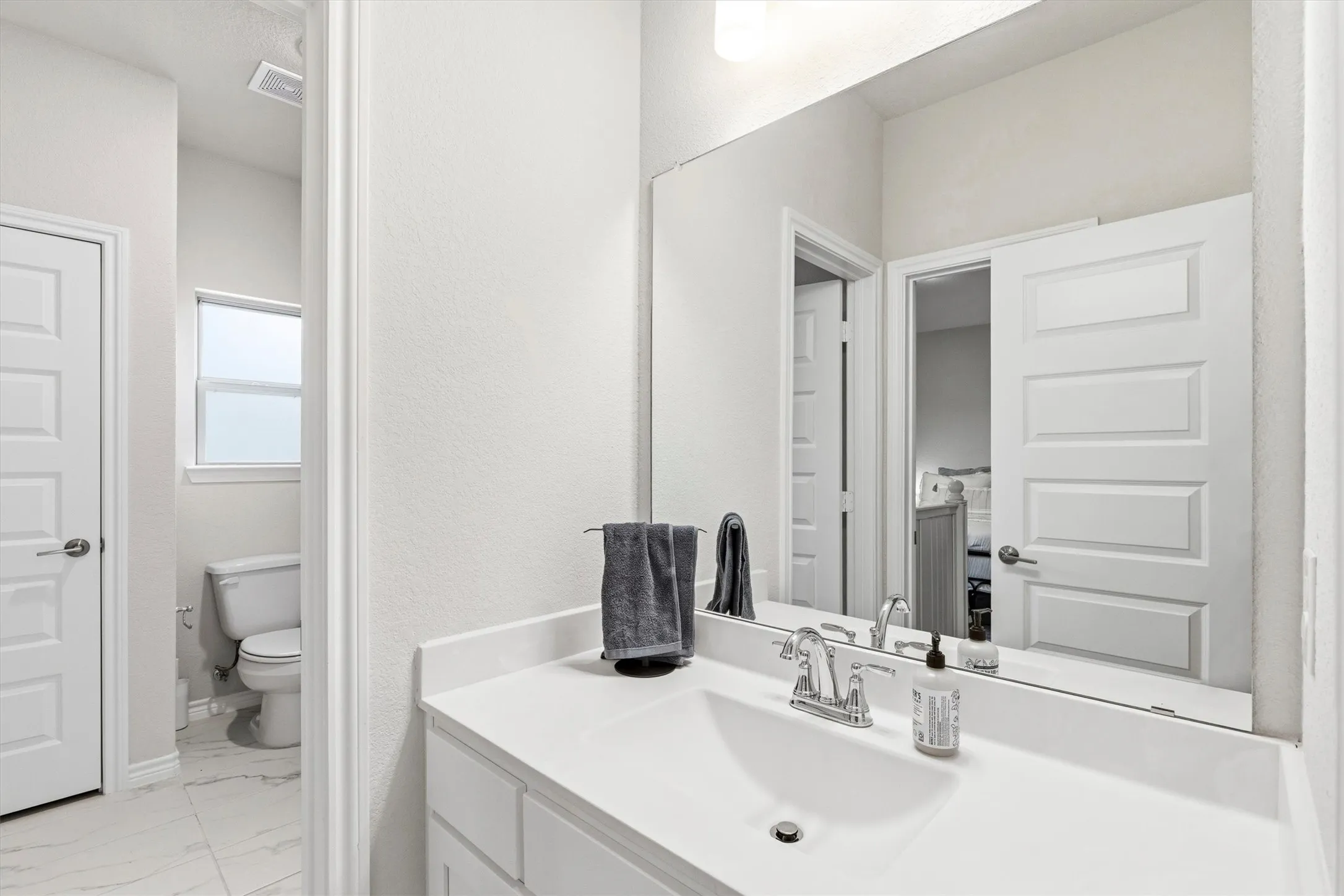 Bathroom vanity featuring a white rectangular undermount sink, chrome faucet, and white countertop