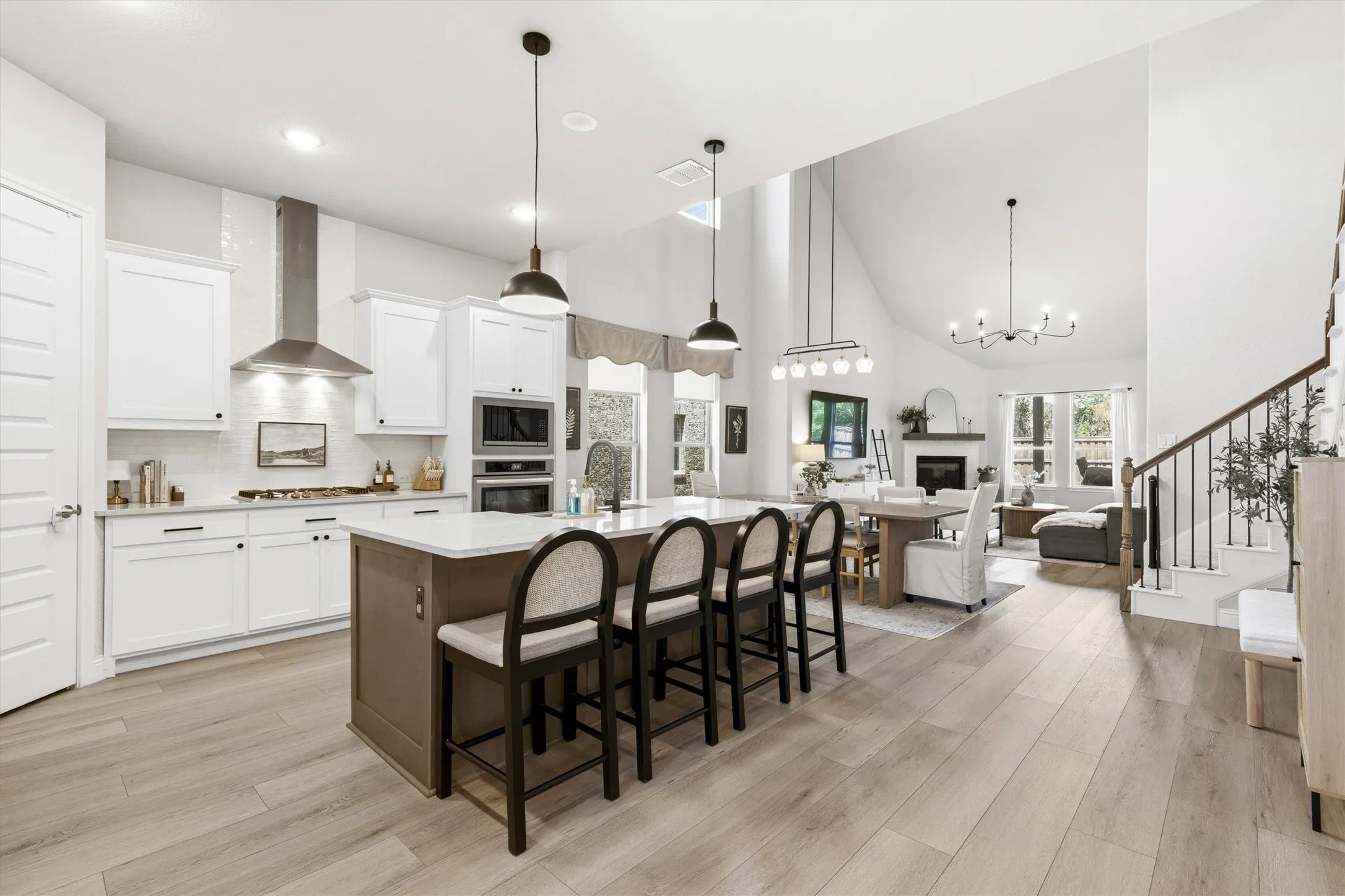 Kitchen featuring a center island with seating, white shaker-style cabinetry, stainless steel appliances, and wood-finish flooring