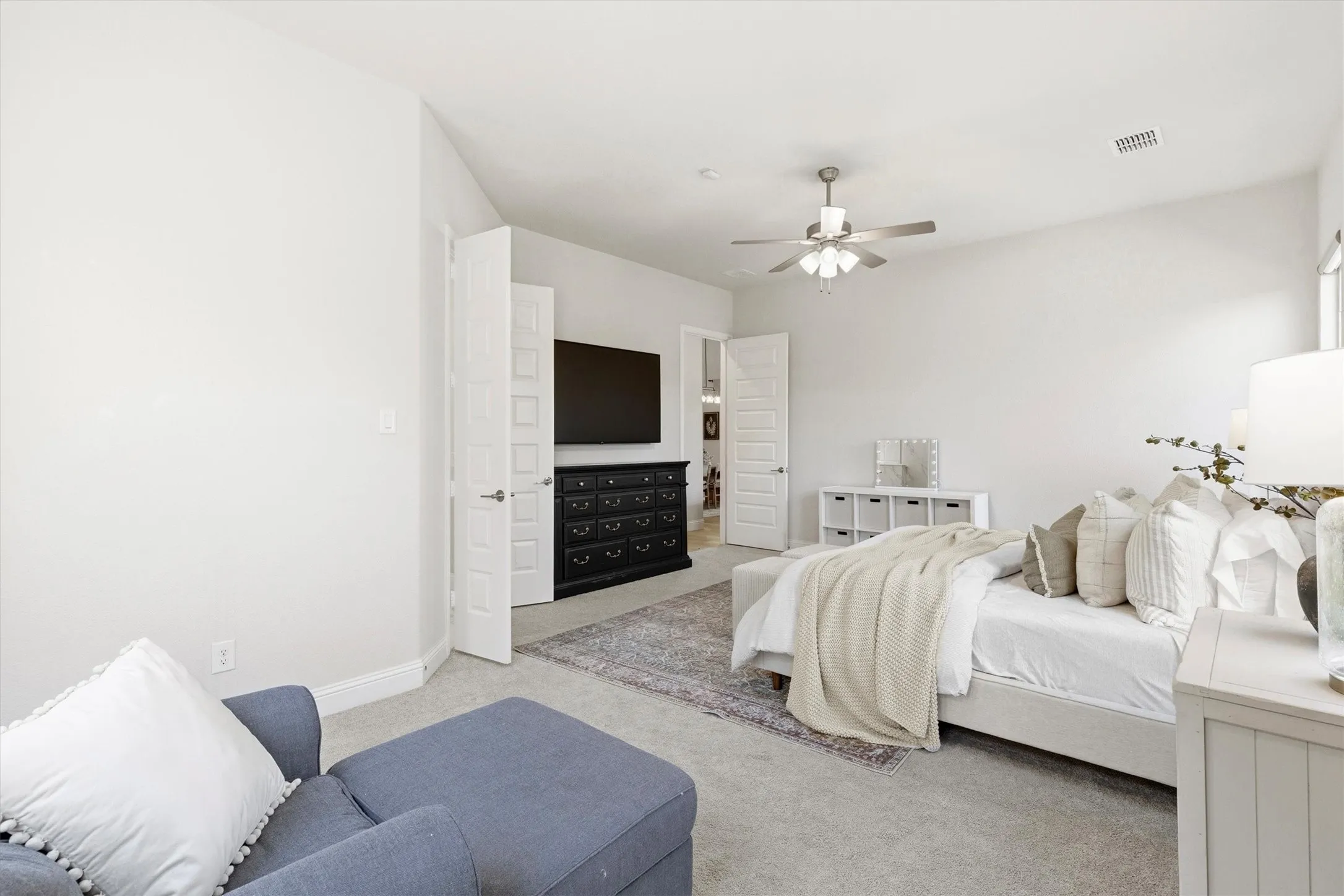 Vaulted ceiling bedroom featuring light gray carpeting, neutral wall finishes, a ceiling fan, and two interior doors